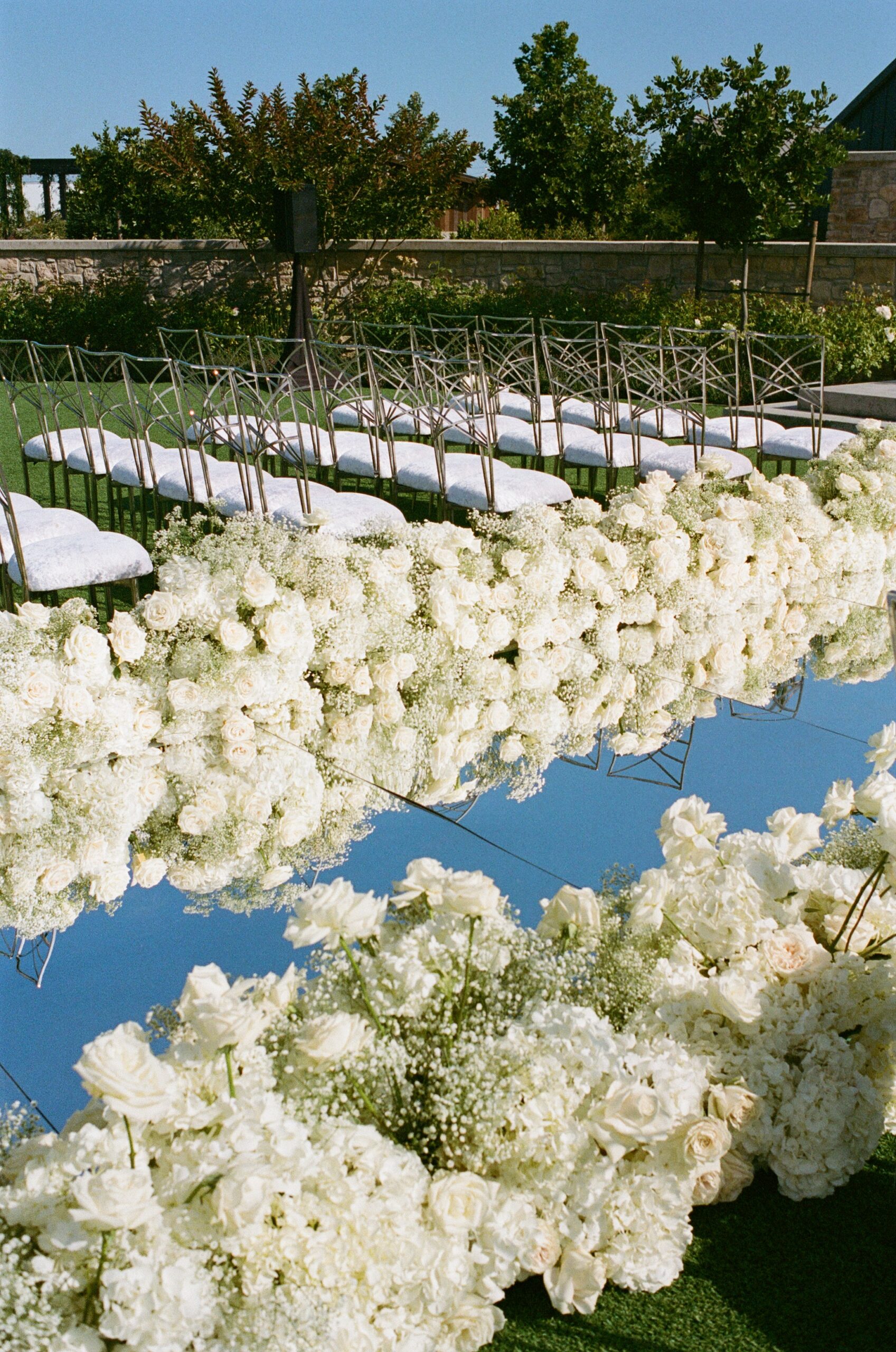 Film wedding photo of the mirror wedding aisle lined by white flowers