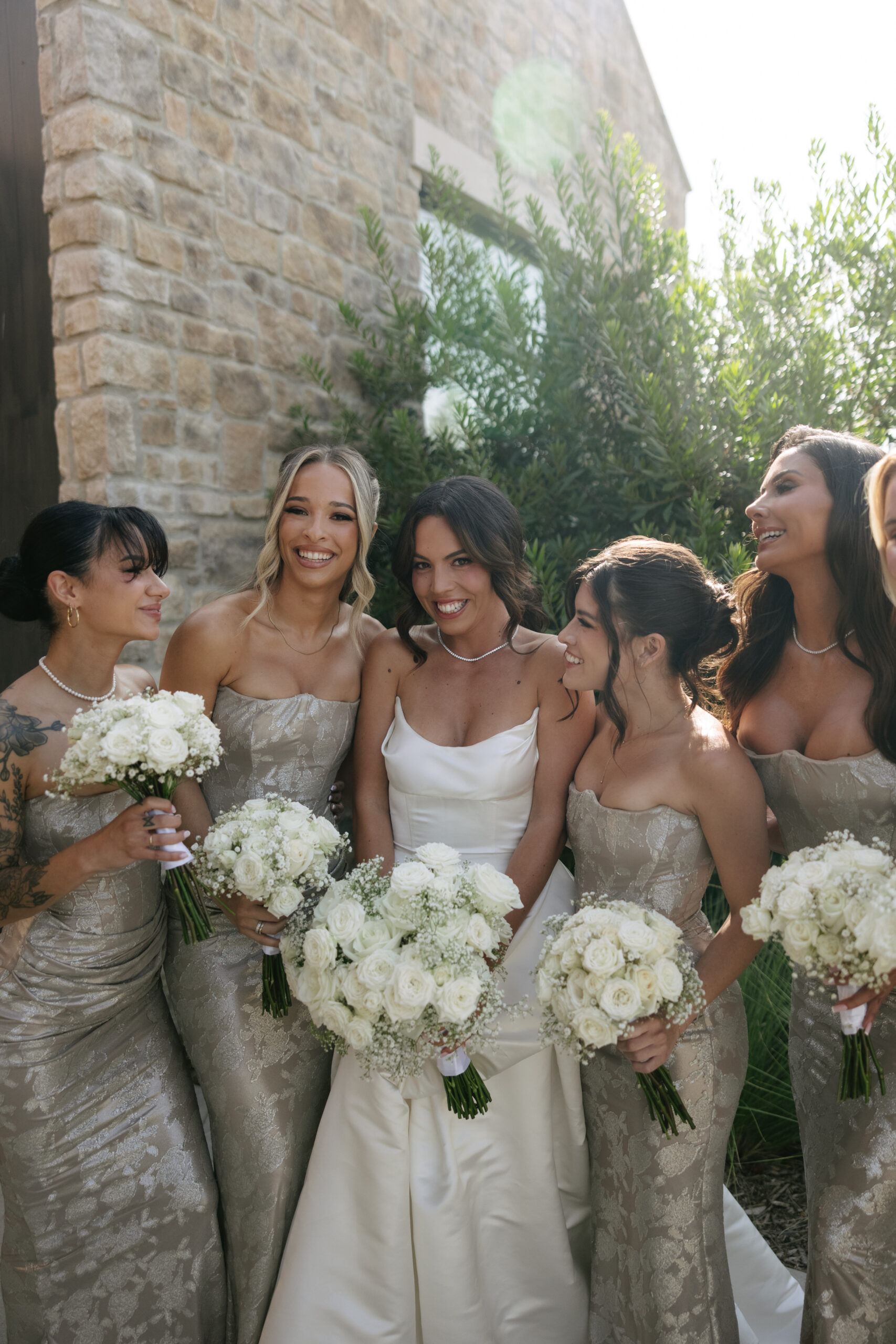 Bride posing with her bridesmaids surrounding her smiling at her