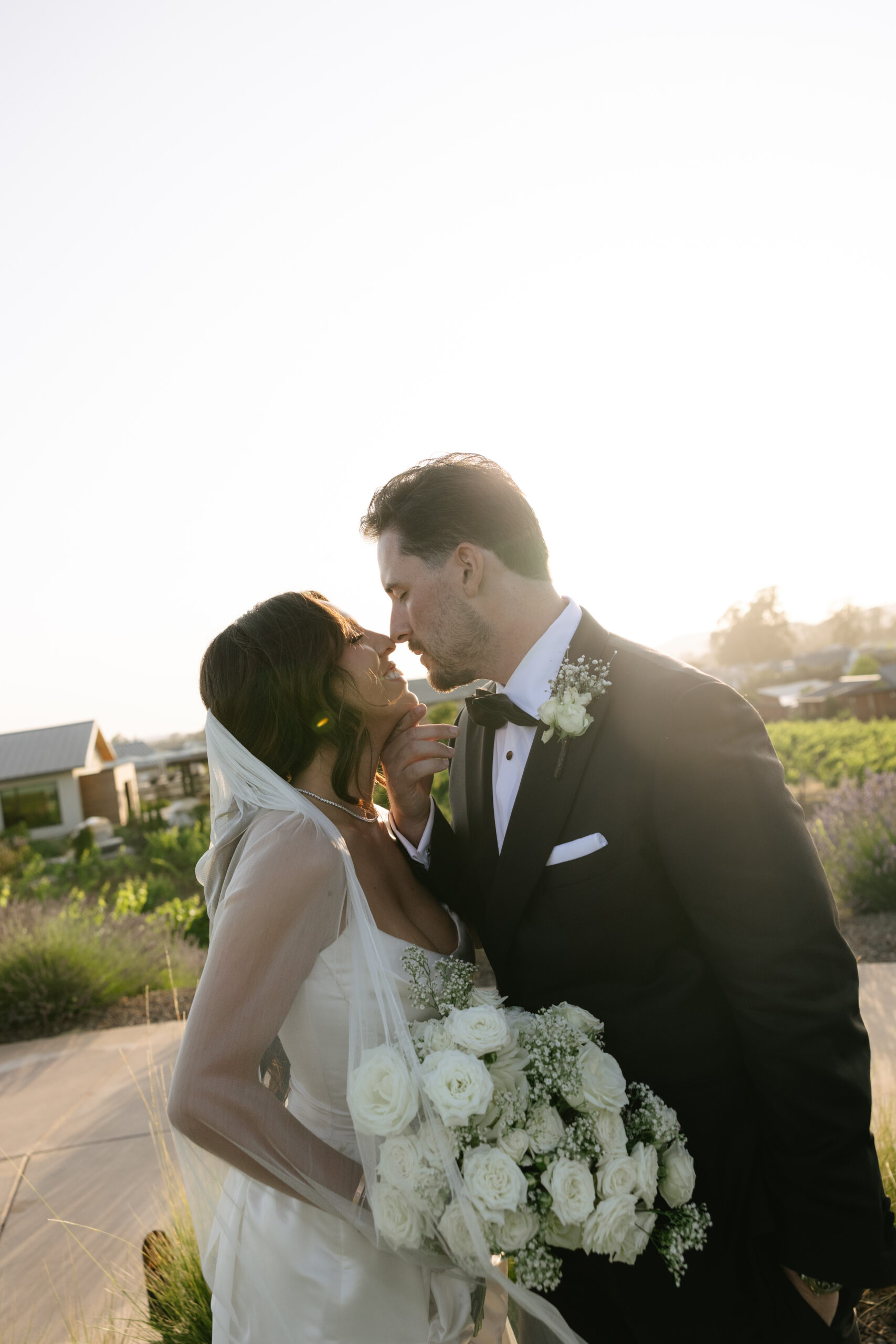 Bride and groom leaning in for a kiss during sunset wedding photos
