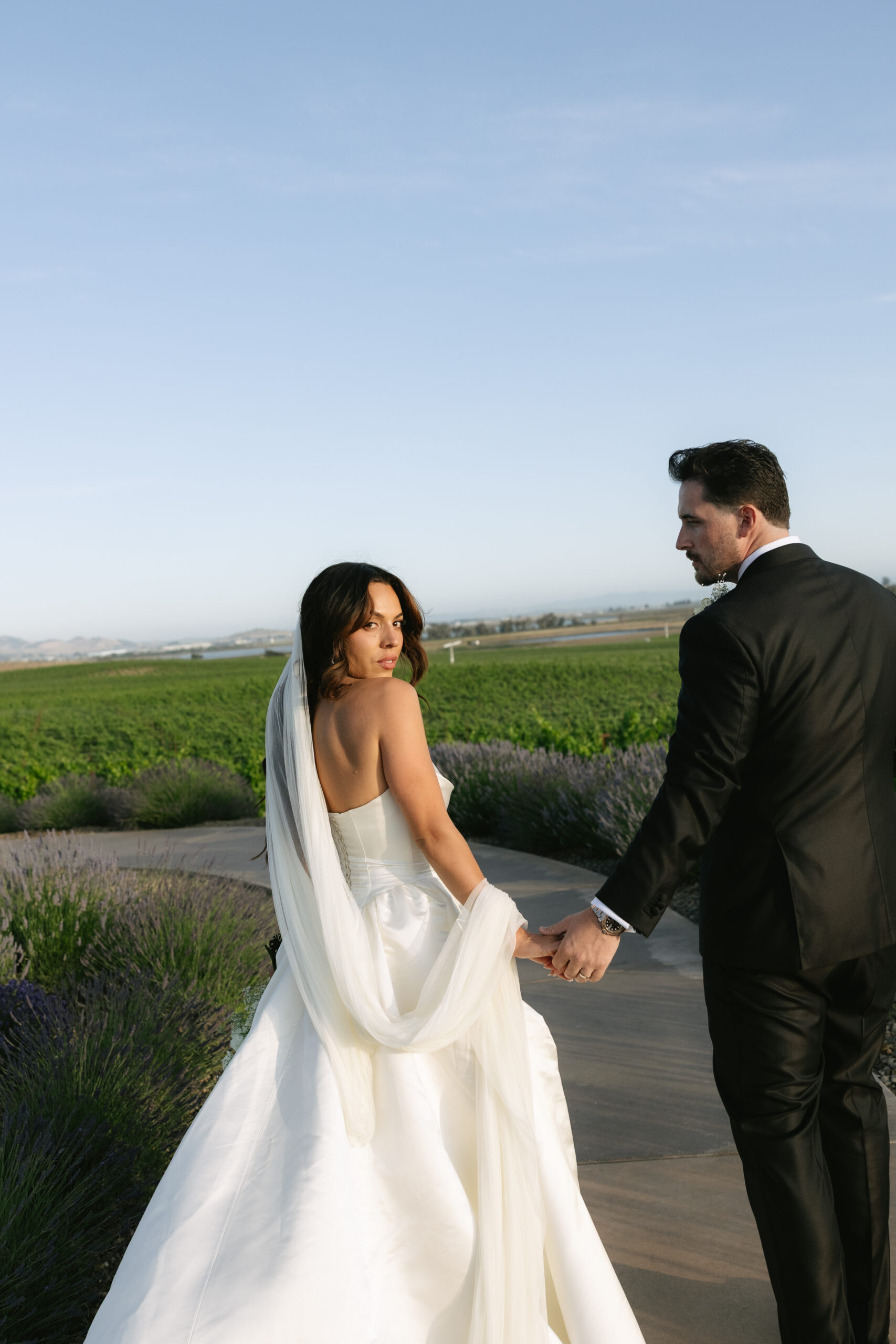 Bride and groom walking away from the camera with bride looking over her shoulder