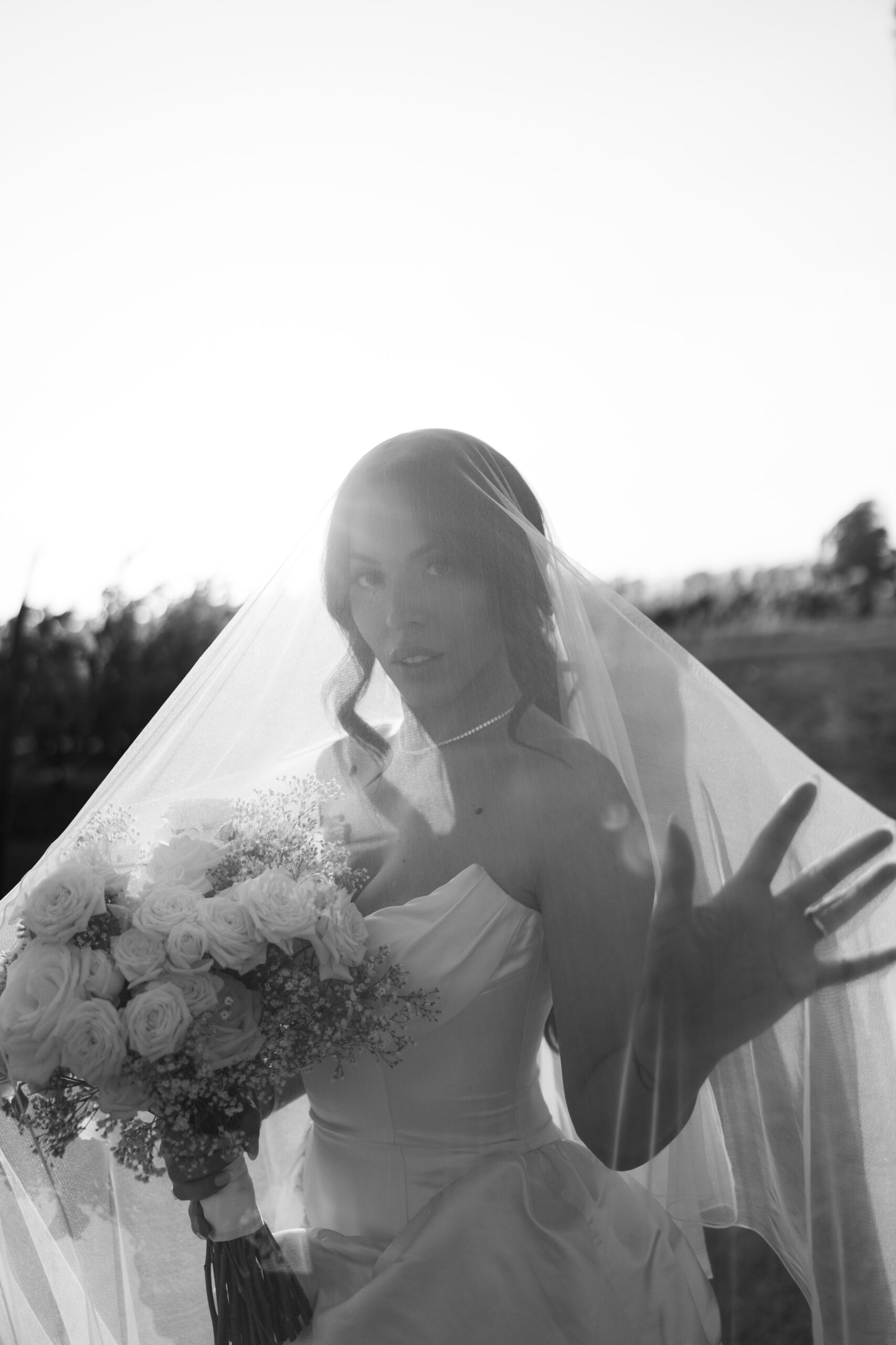 Bridal portrait of bride underneath her veil with the sun hitting behind her