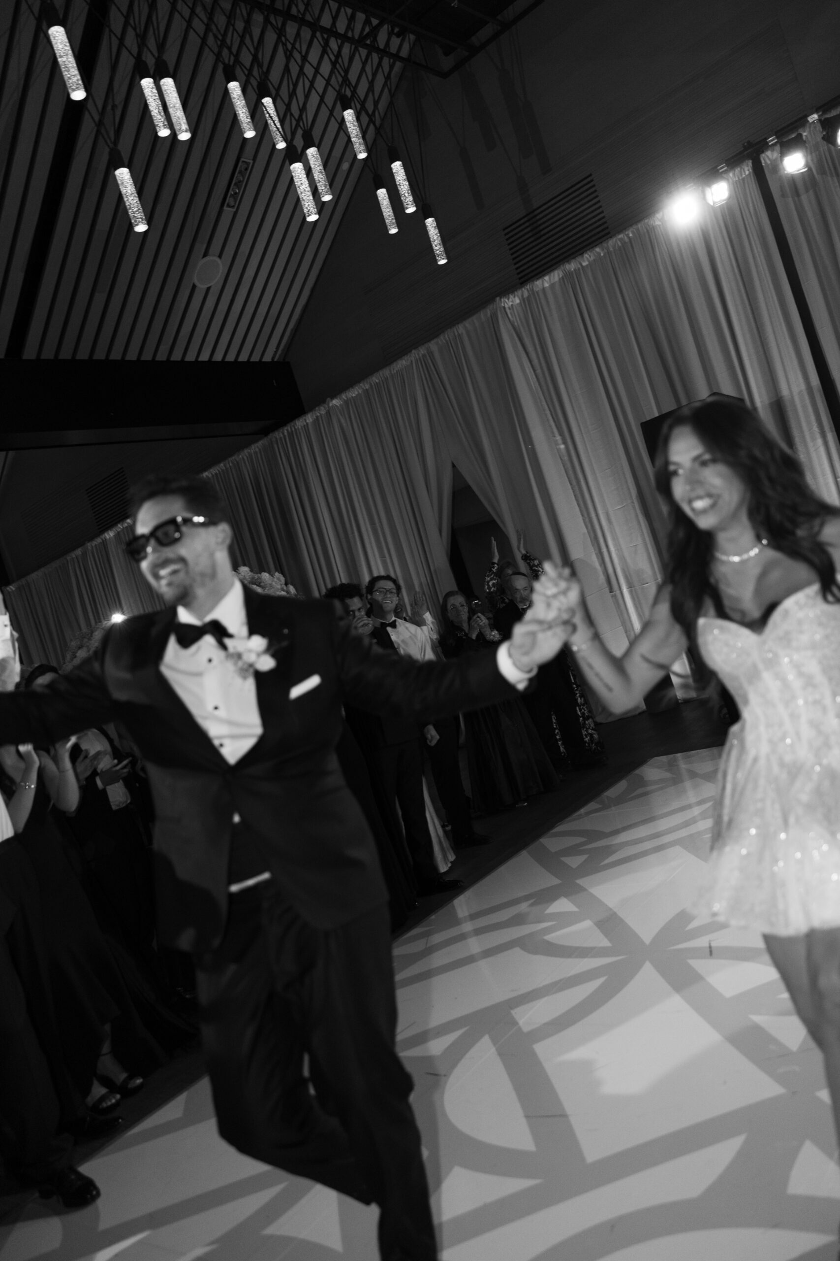 Bride and groom dancing during their wedding reception, with bride wearing a short reception dress