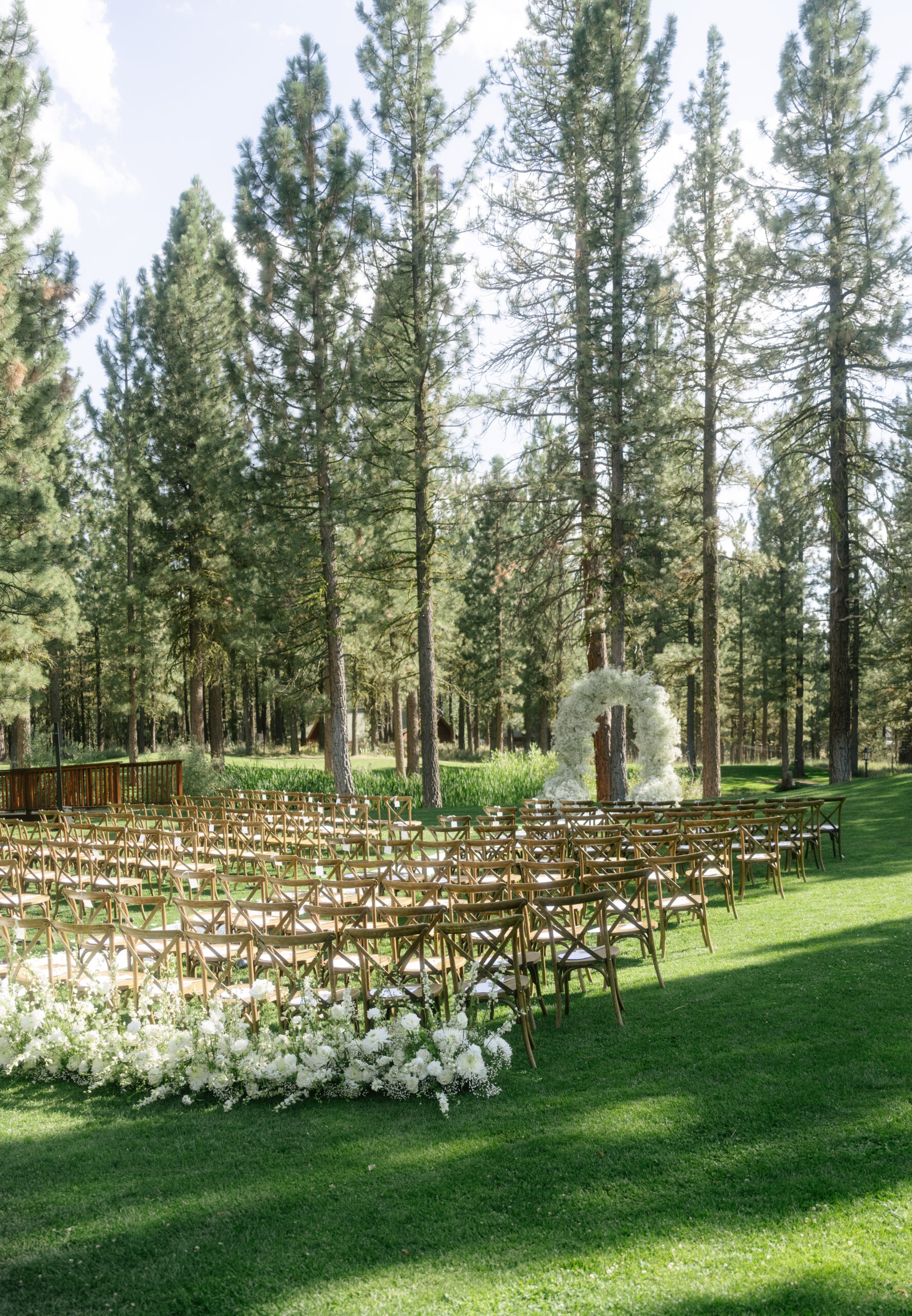 Chairs setup for wedding ceremony in a forest wedding venue with a floral arch