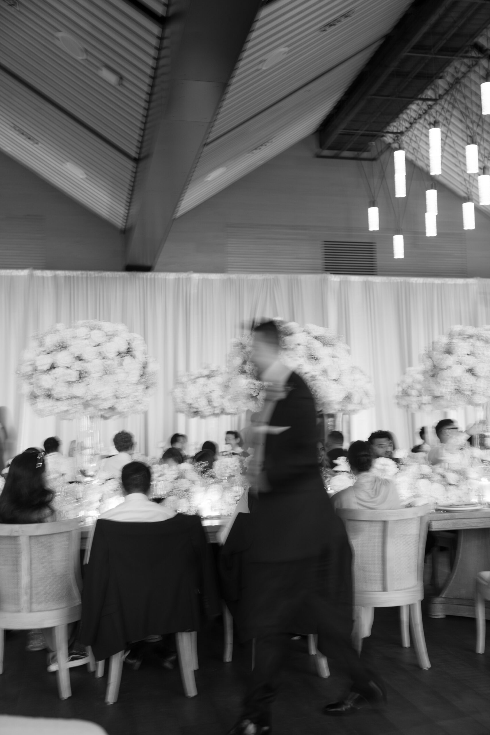 Blurry wedding photo of groom walking past a dinner table
