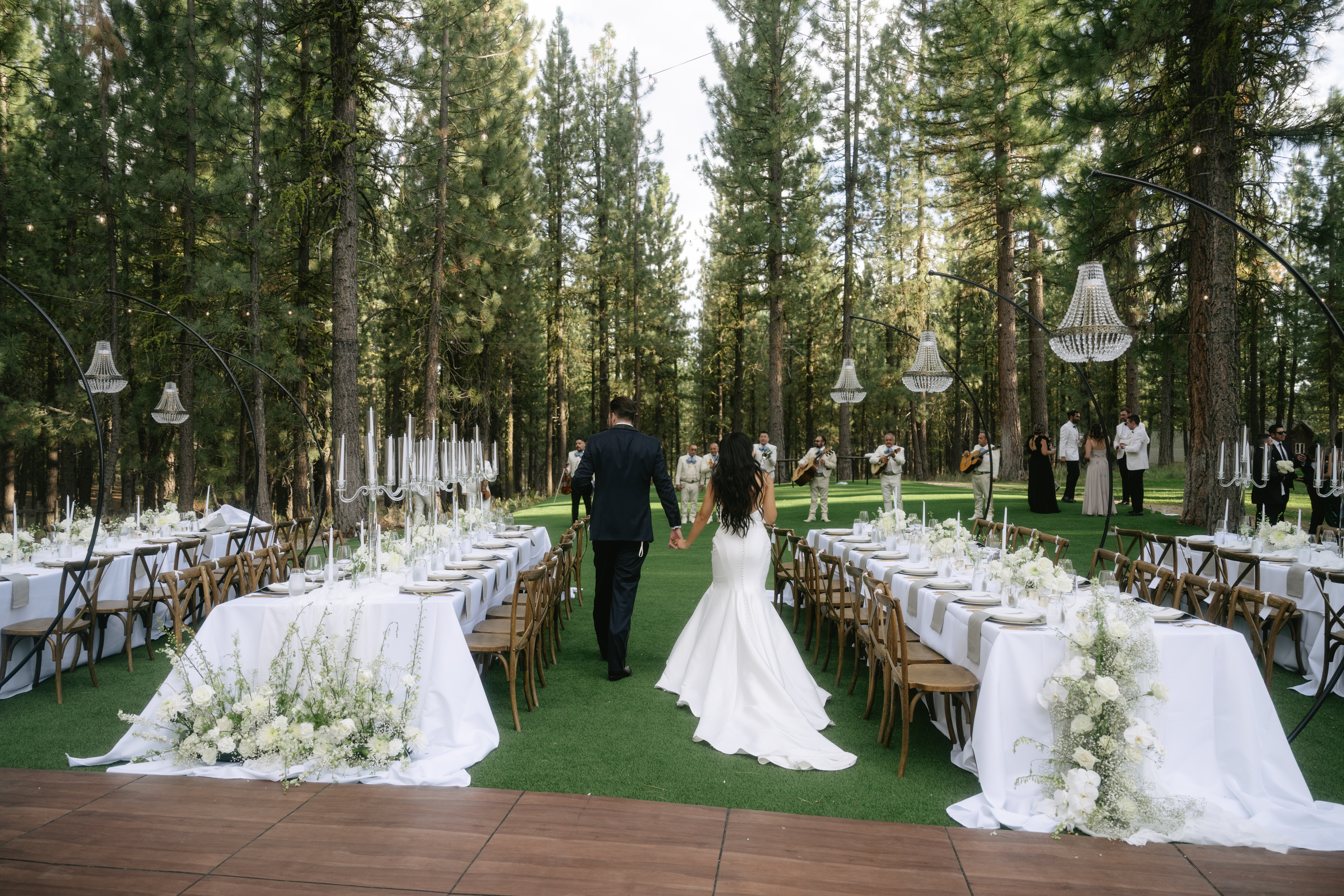 Couple walking through their outdoor wedding reception with a live band playing music behind them