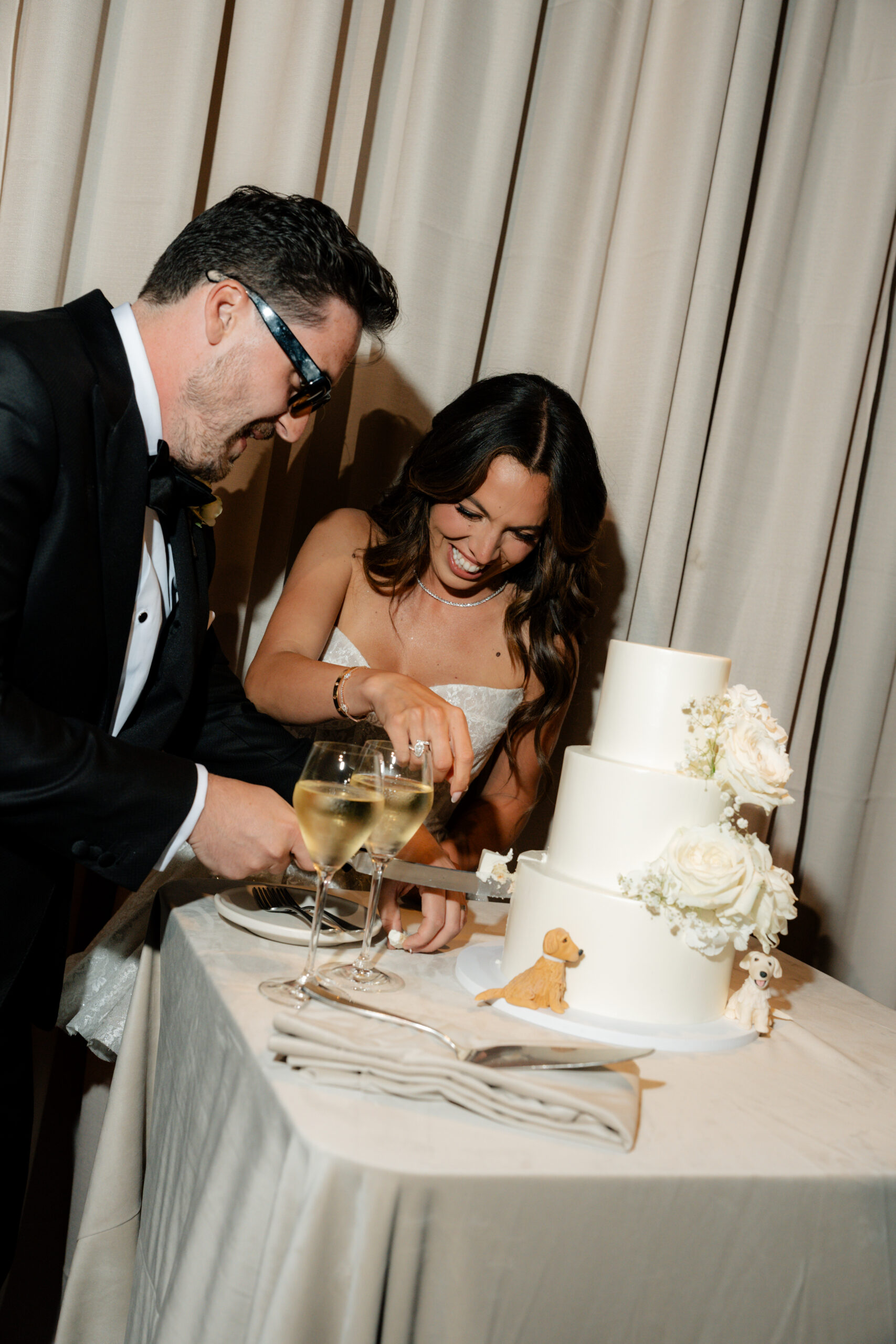 Bride and groom laughing while cutting their cake