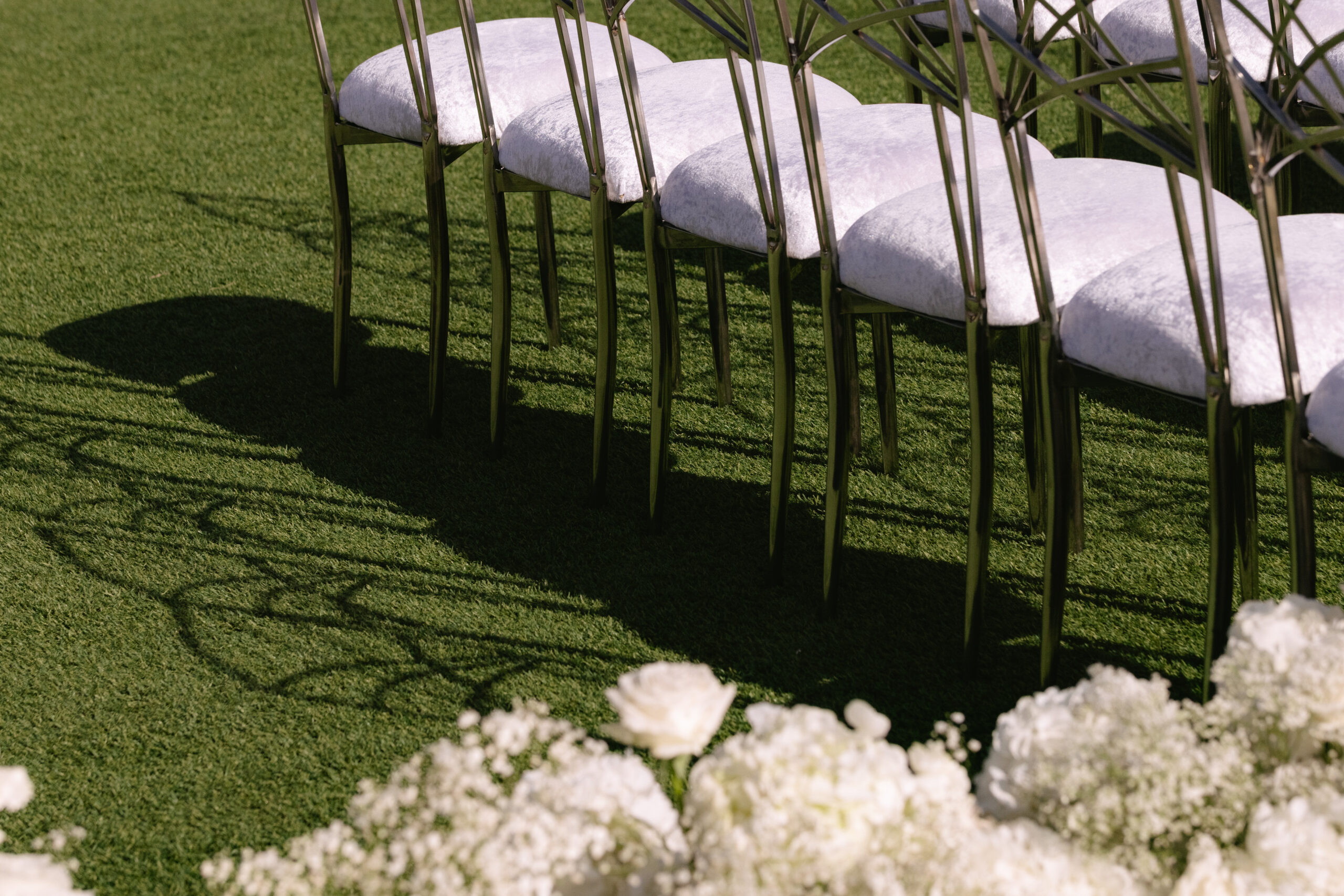 The back row of wedding chairs set up at a Napa Valley wedding venue with white flowers on the wedding aisle