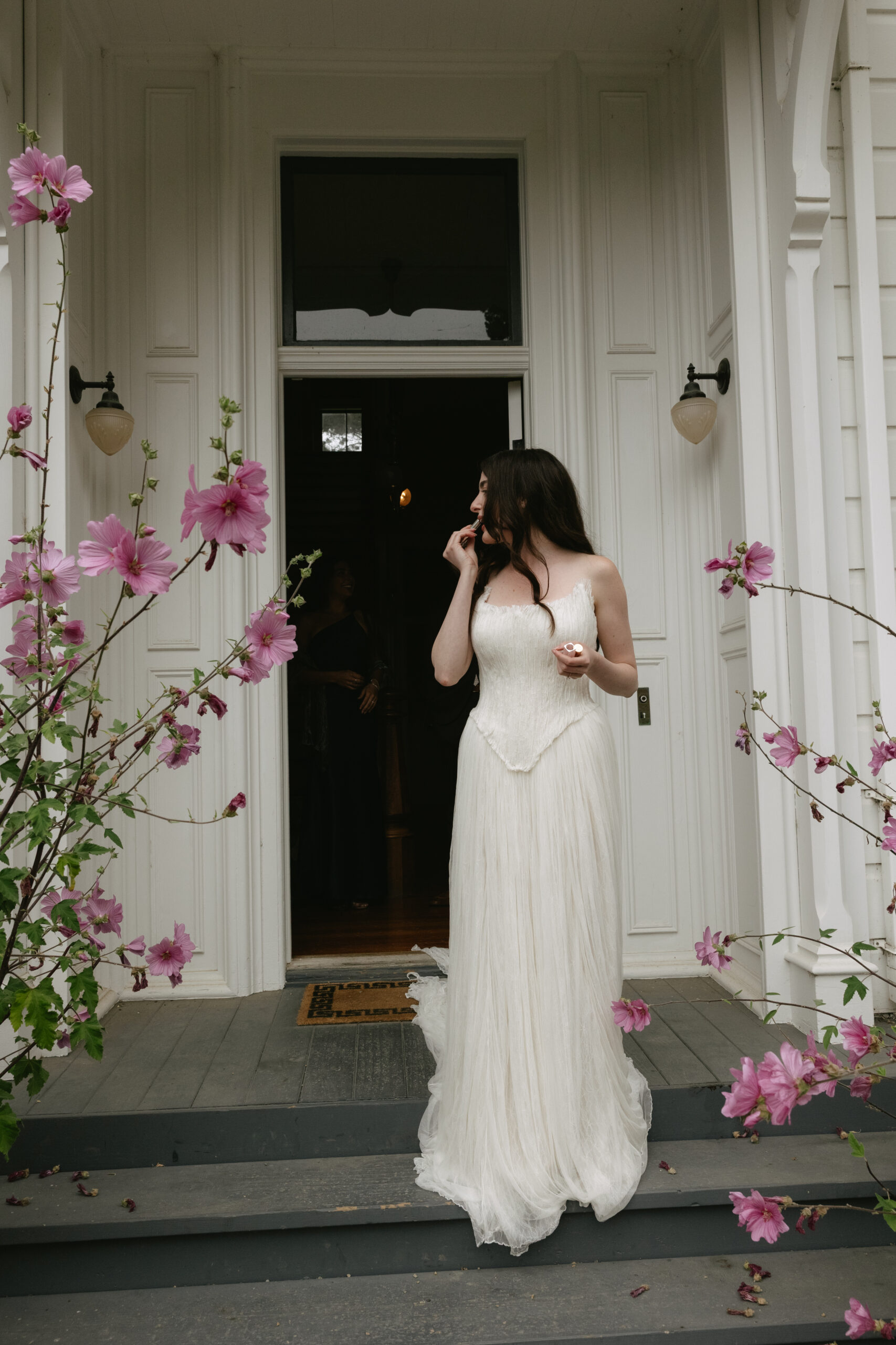 Bride applying lipstick on front porch of historic house at Switzer Farm