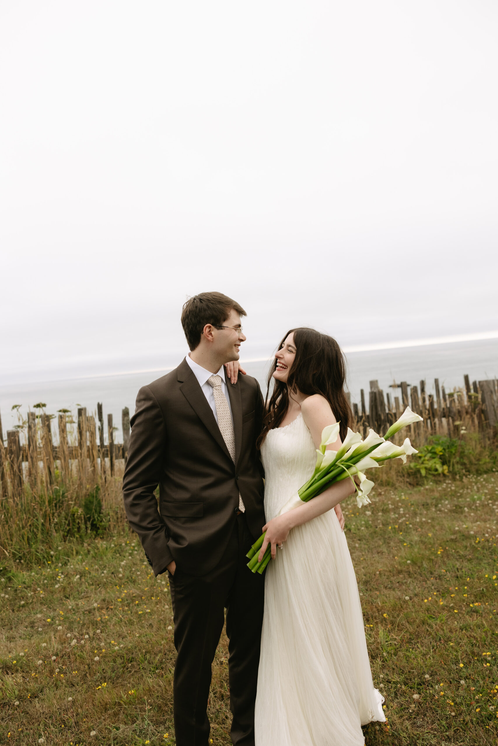 Bride and groom laughing at each other at waterfront ceremony spot