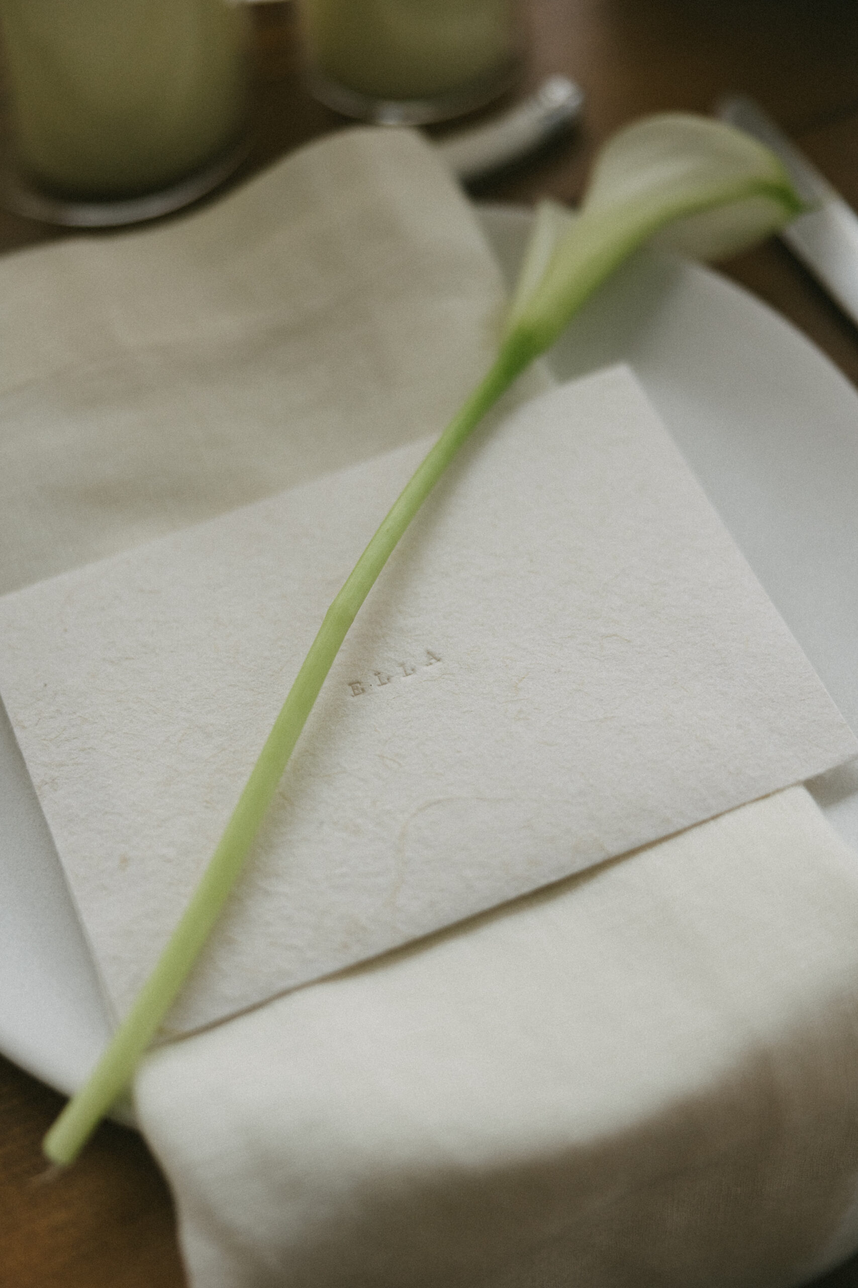 A single calla lily laid on top of a personalized note to a wedding guest