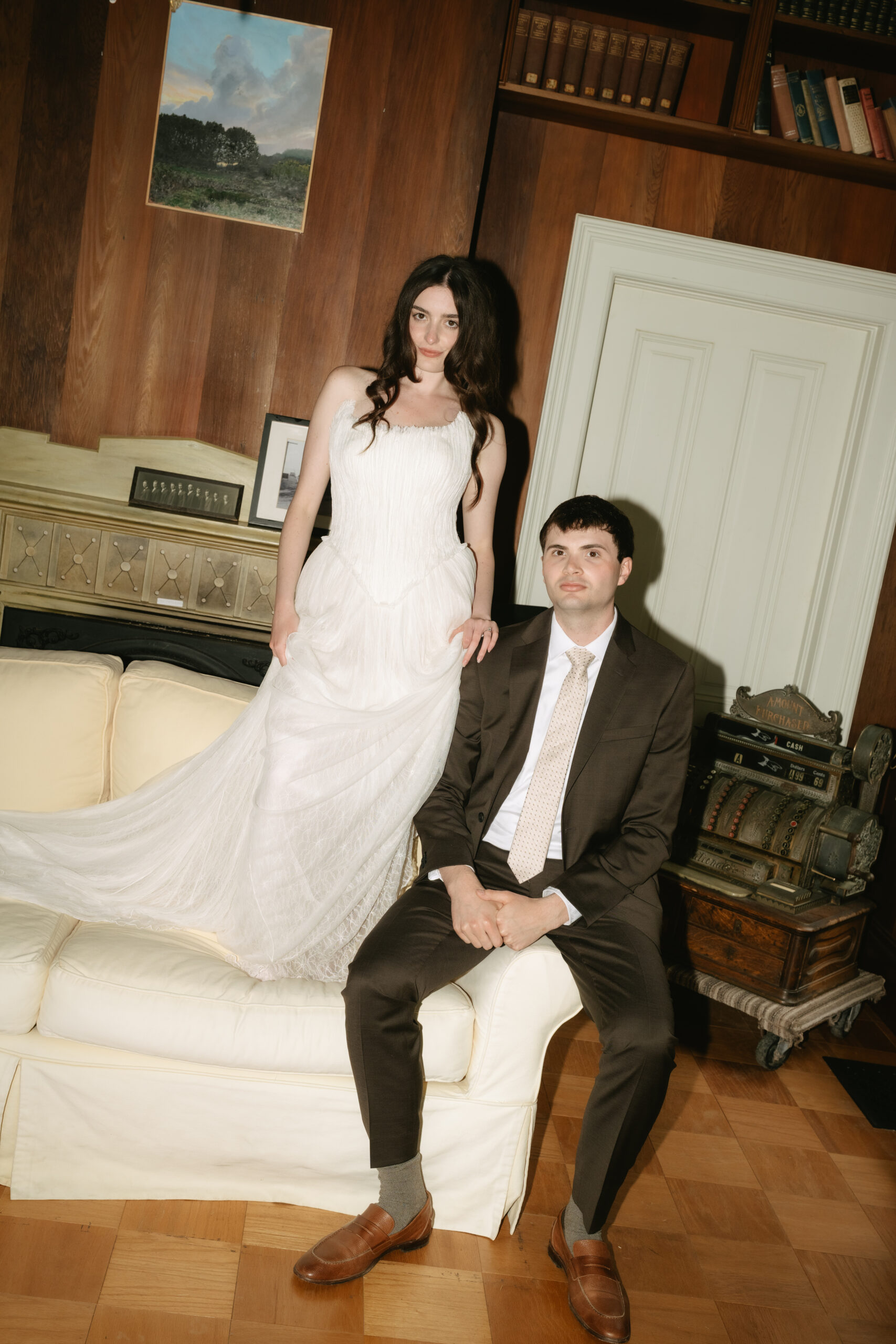 Bride standing on the couch beside groom posing for an editorial wedding photo