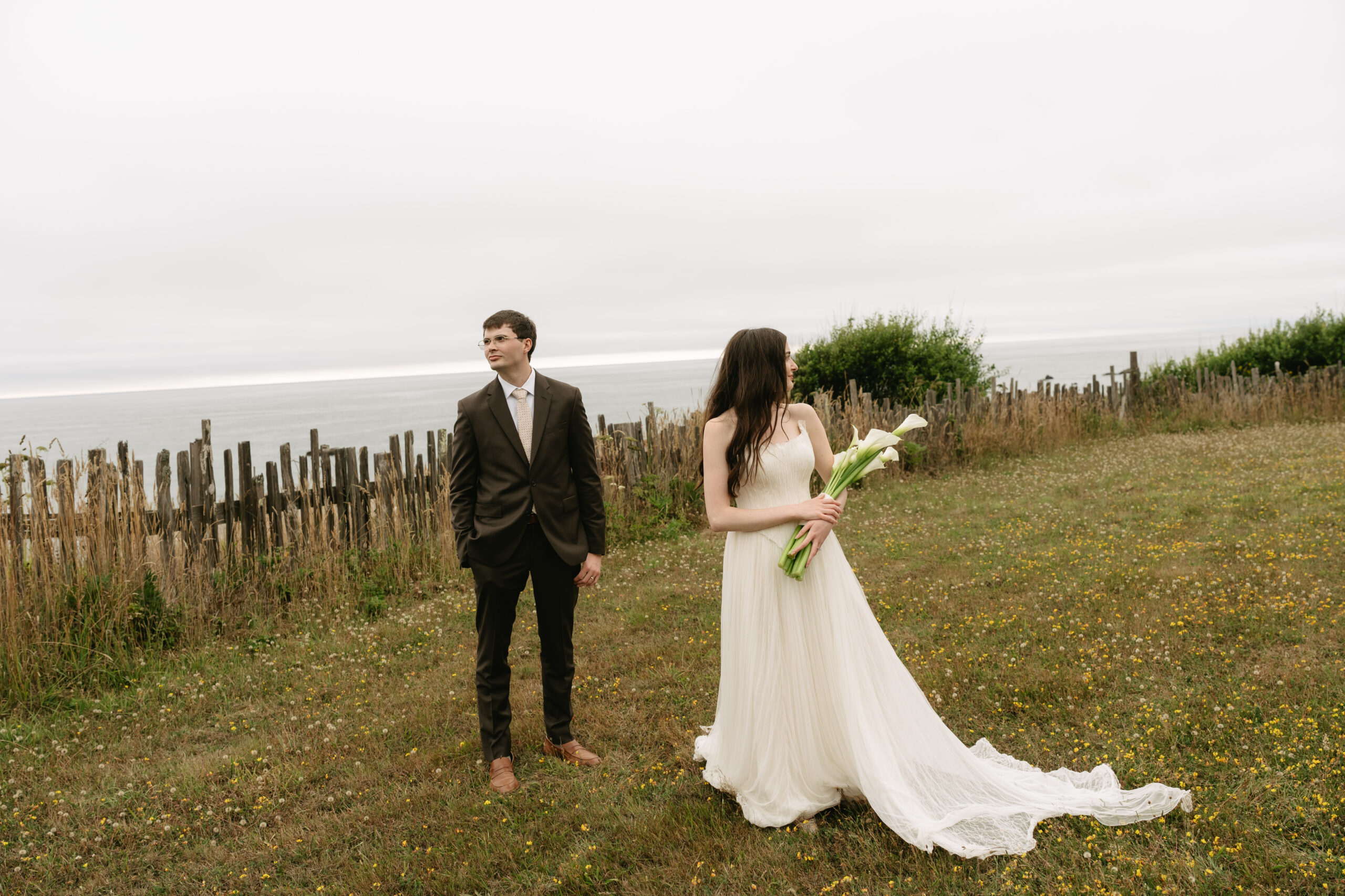 Bride and groom posing for an editorial wedding photo in front of the oceanfront views at Switzer Farm
