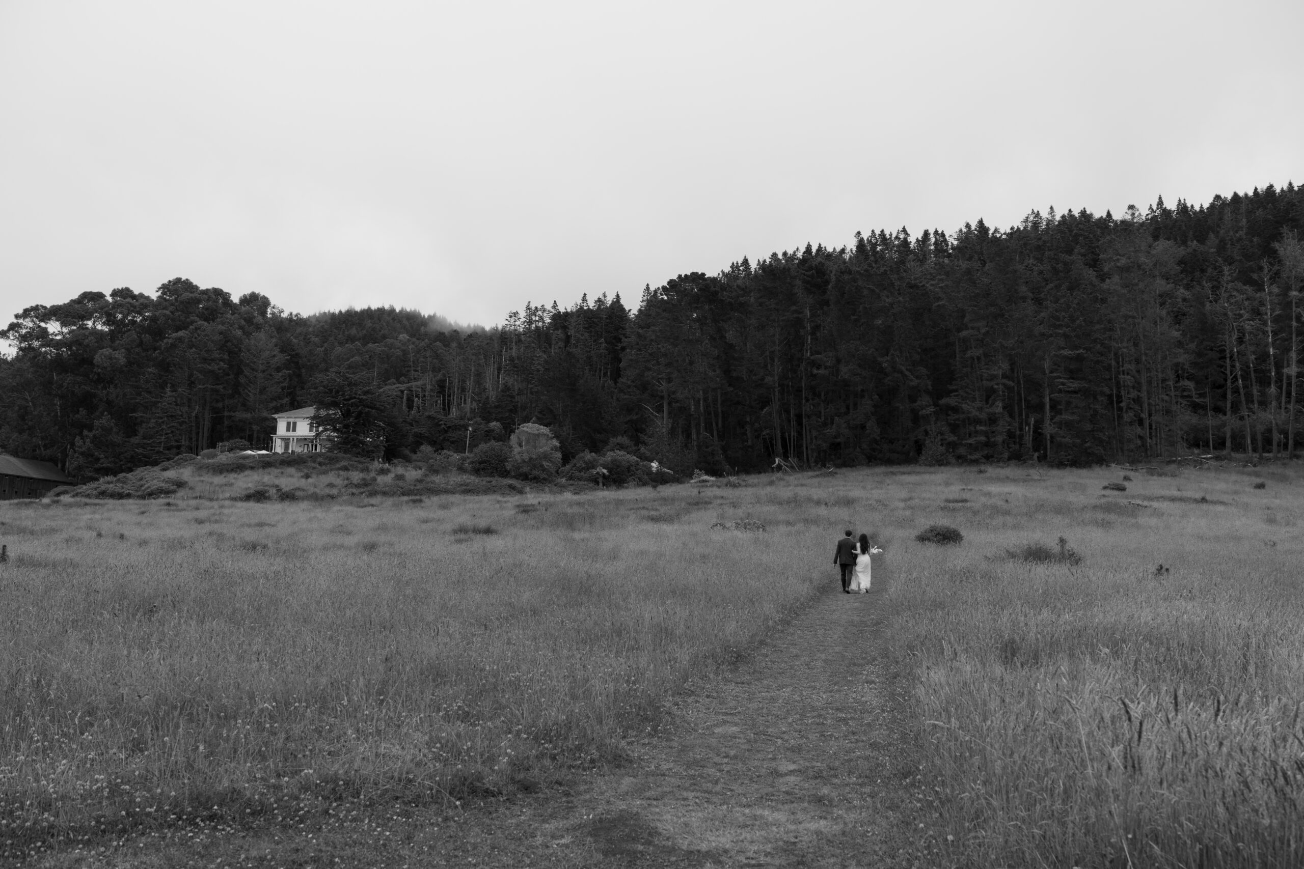 Bride and groom walking back to the historic house at Switzer Farm through the meadows