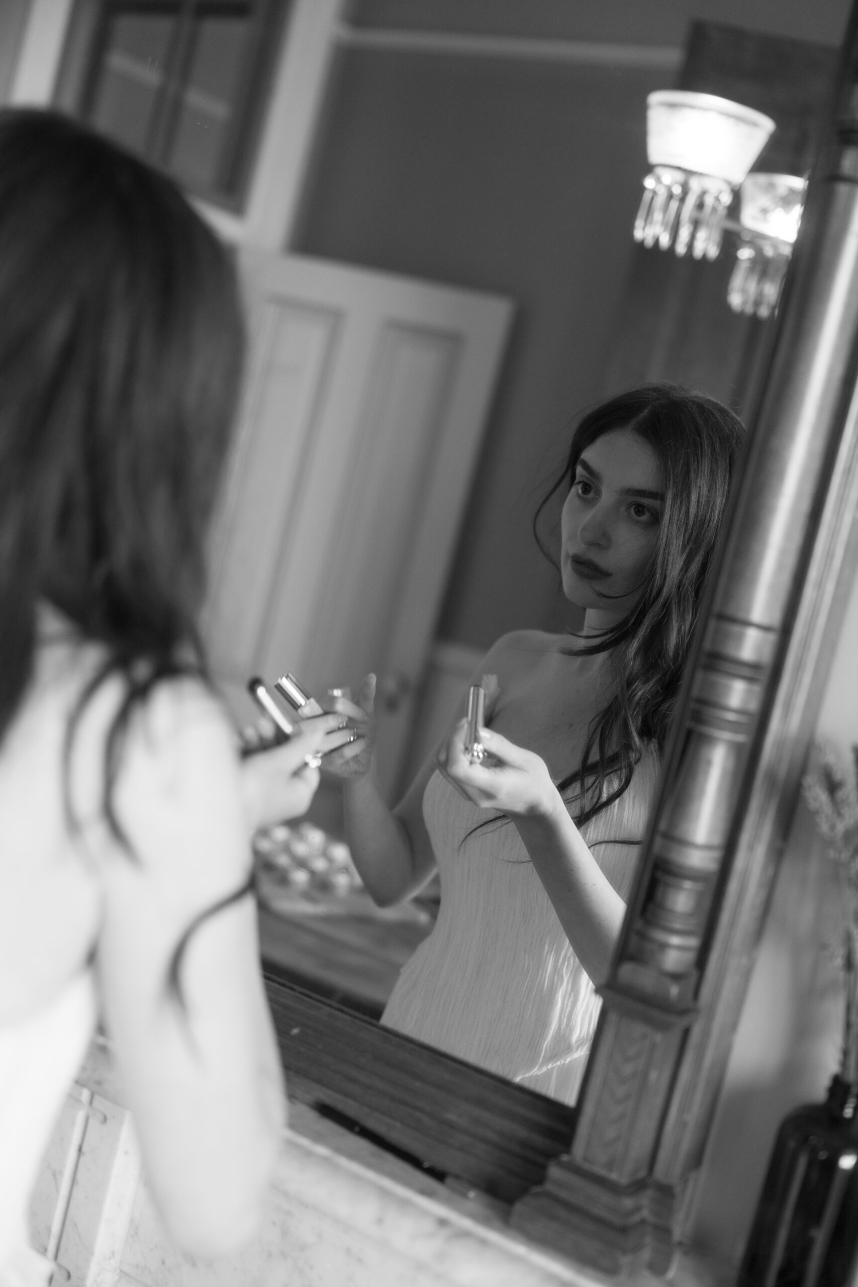 Bride getting ready in a black and white photo where she is looking in the mirror