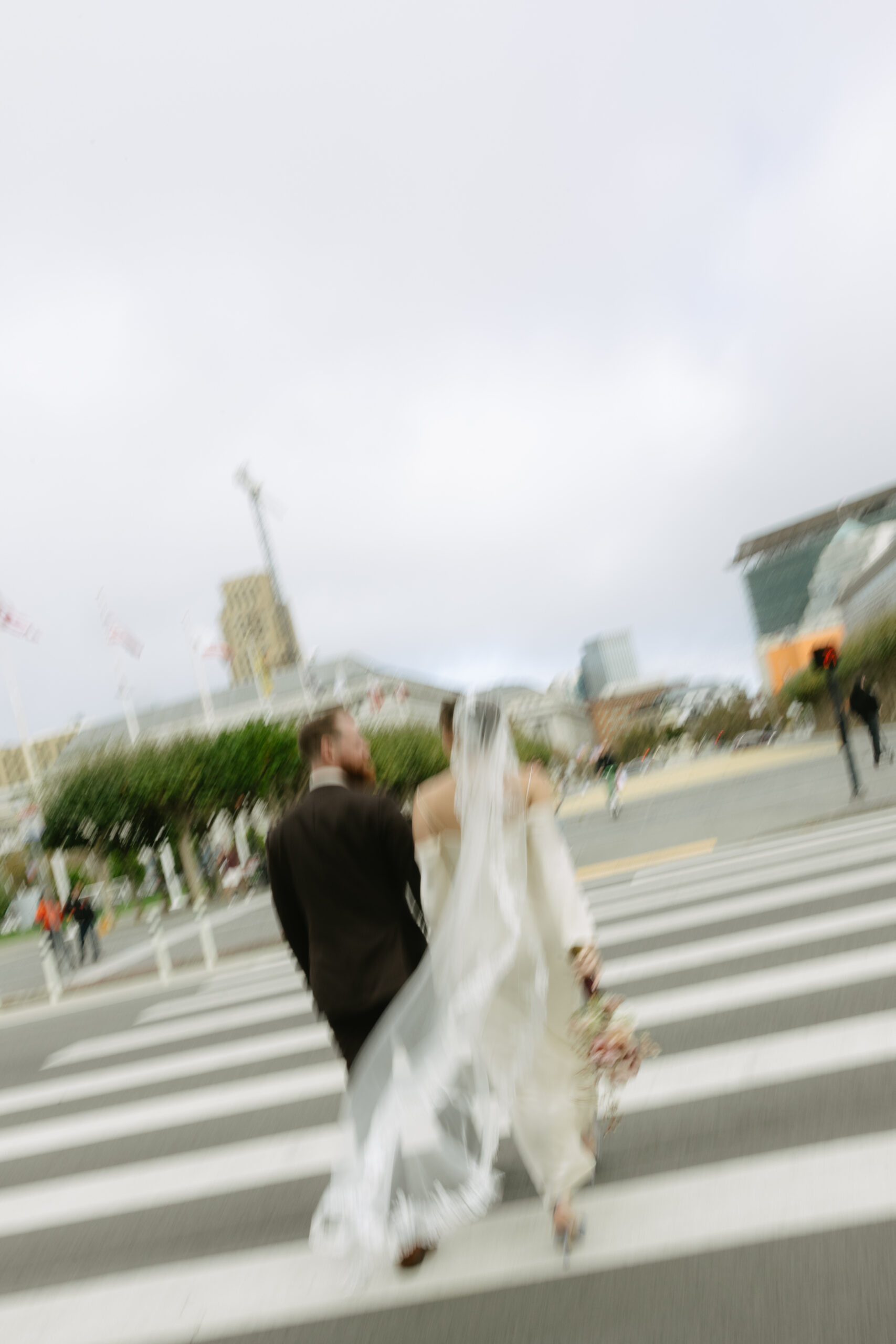 A blurry photo of a bride and groom crossing the street after their elopement