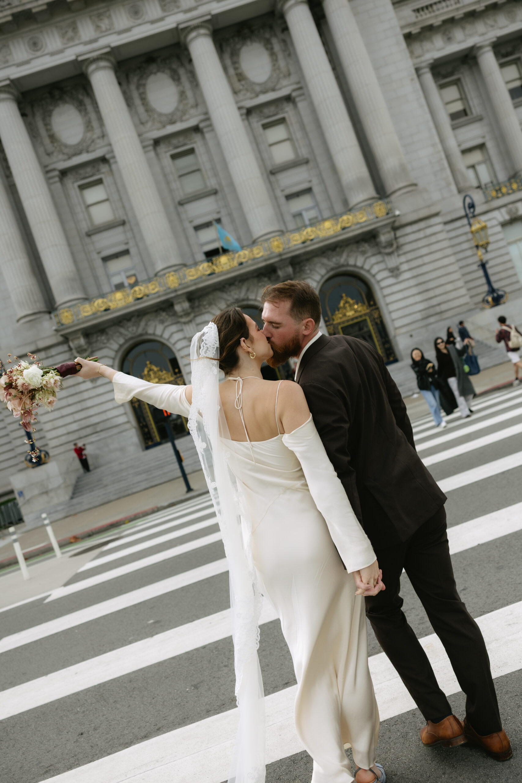 A bride and groom kissing on a crosswalk after their San Francisco city hall wedding