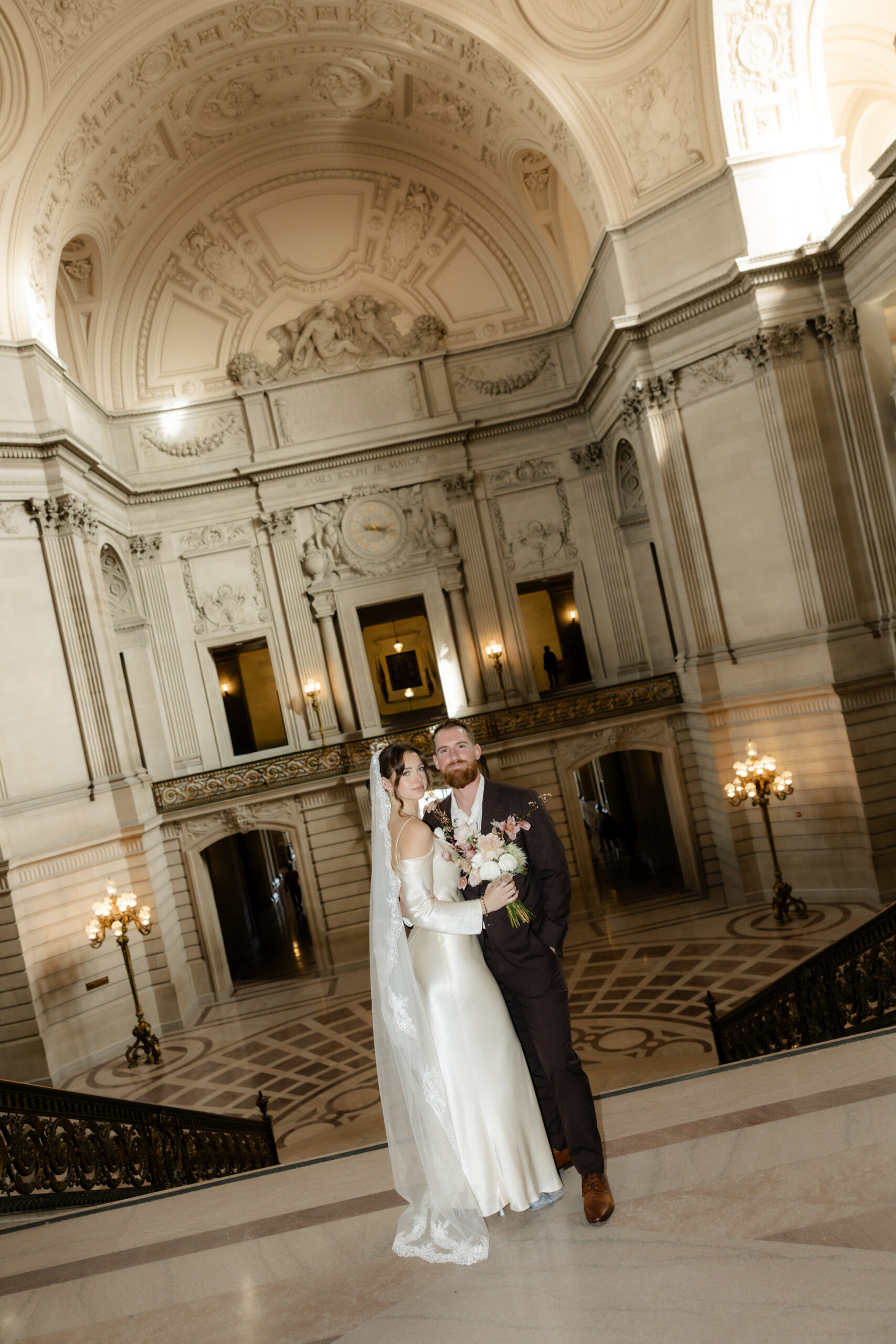 Bride and groom posing in a grand room at their San Francisco City Hall wedding