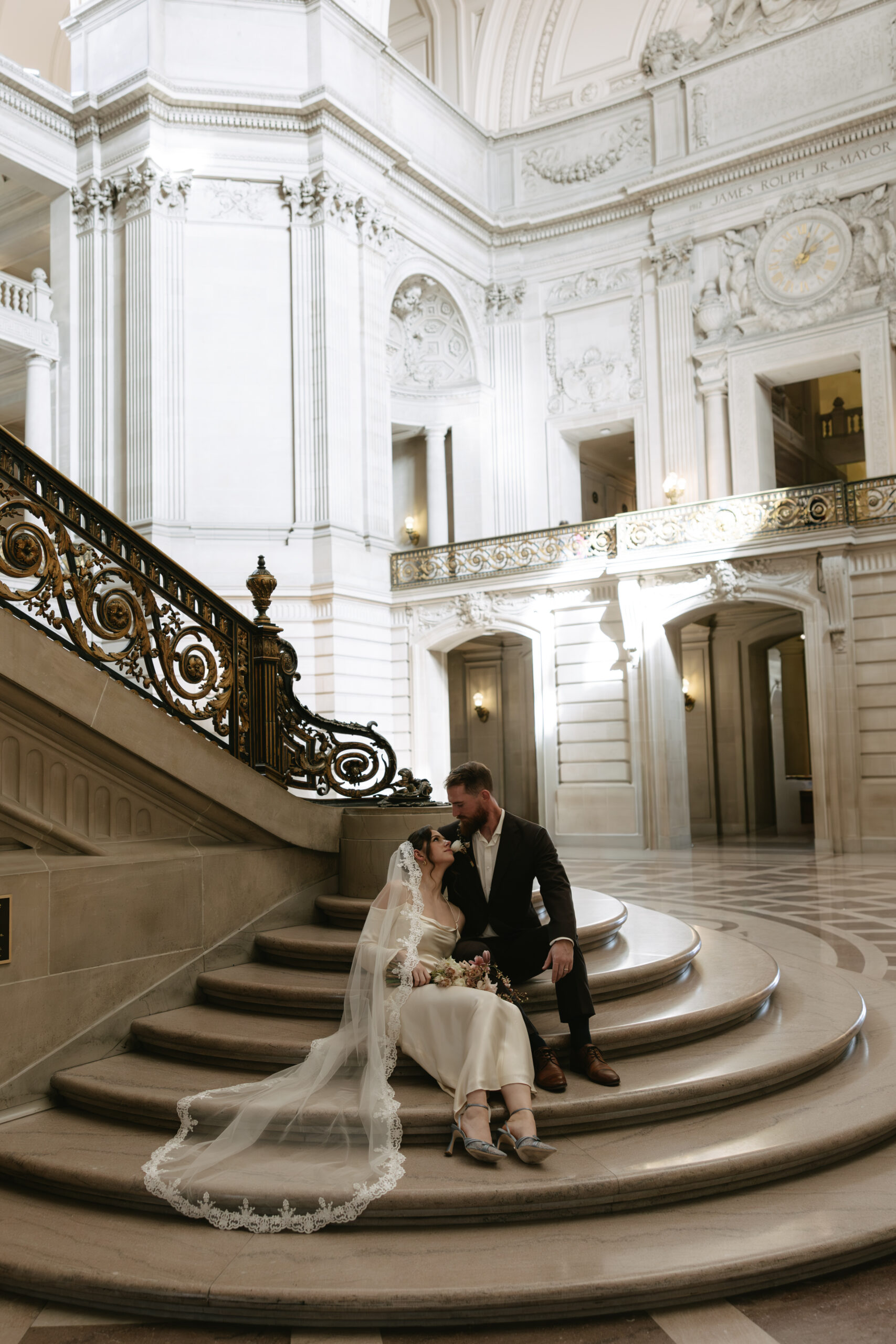 A couple sitting on a grand staircase, one of the location options for a San Francisco City Hall Wedding