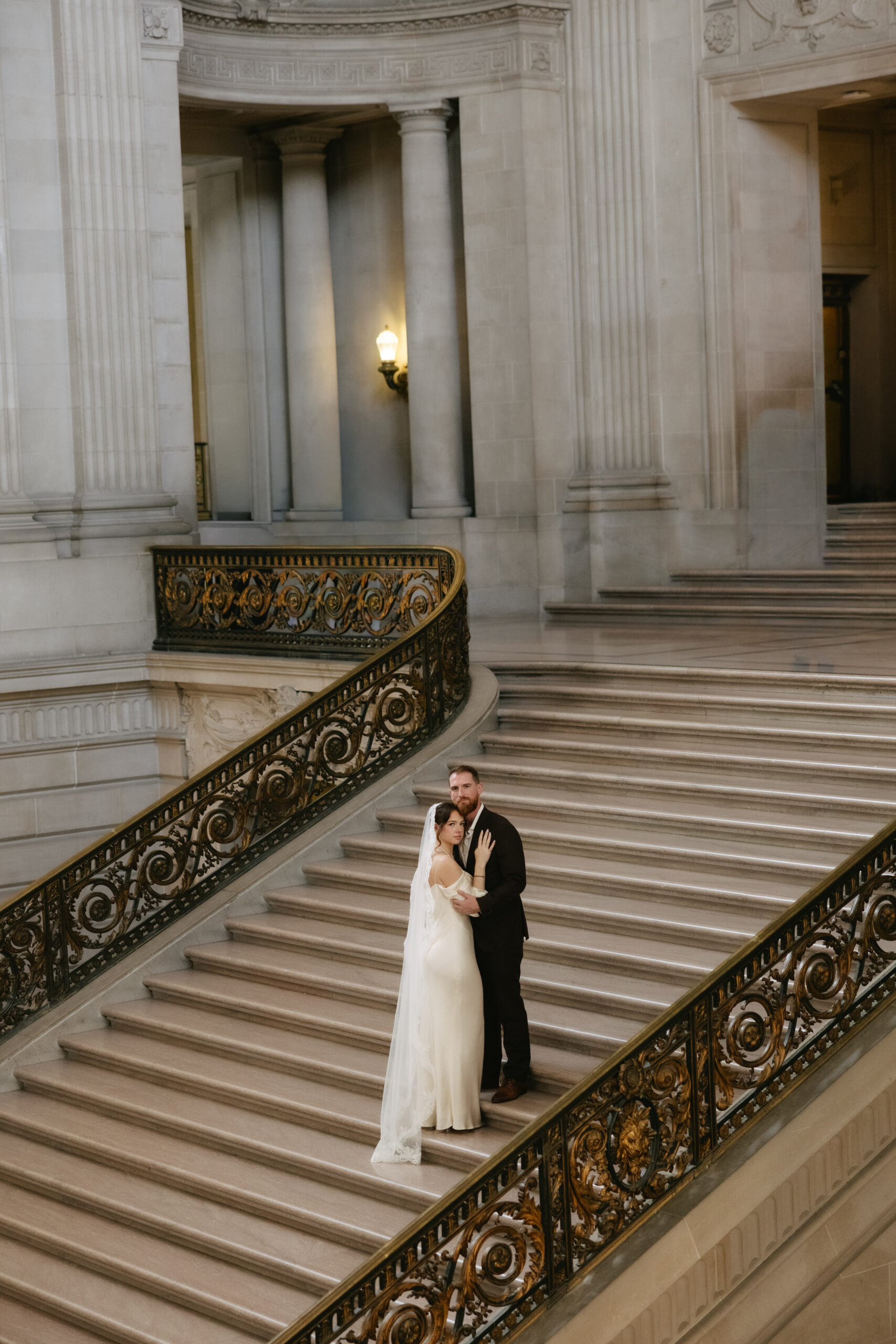 A couple posing for wedding photos on the grand staircase, a San Francisco City Hall wedding location option