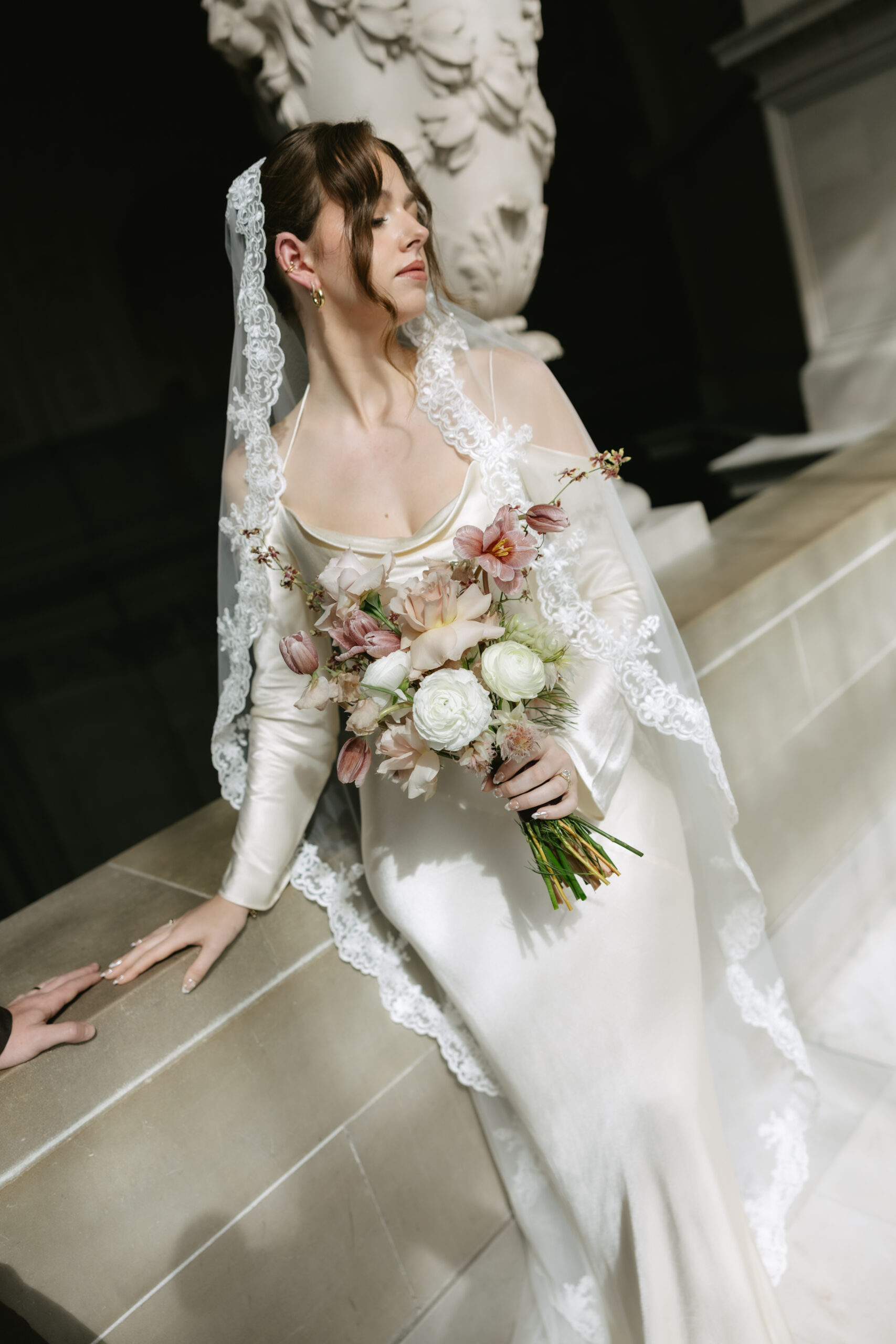 A bridal portrait in the hallway of San Francisco city hall, featuring a bride in a satin long sleeve wedding dress and lace veil