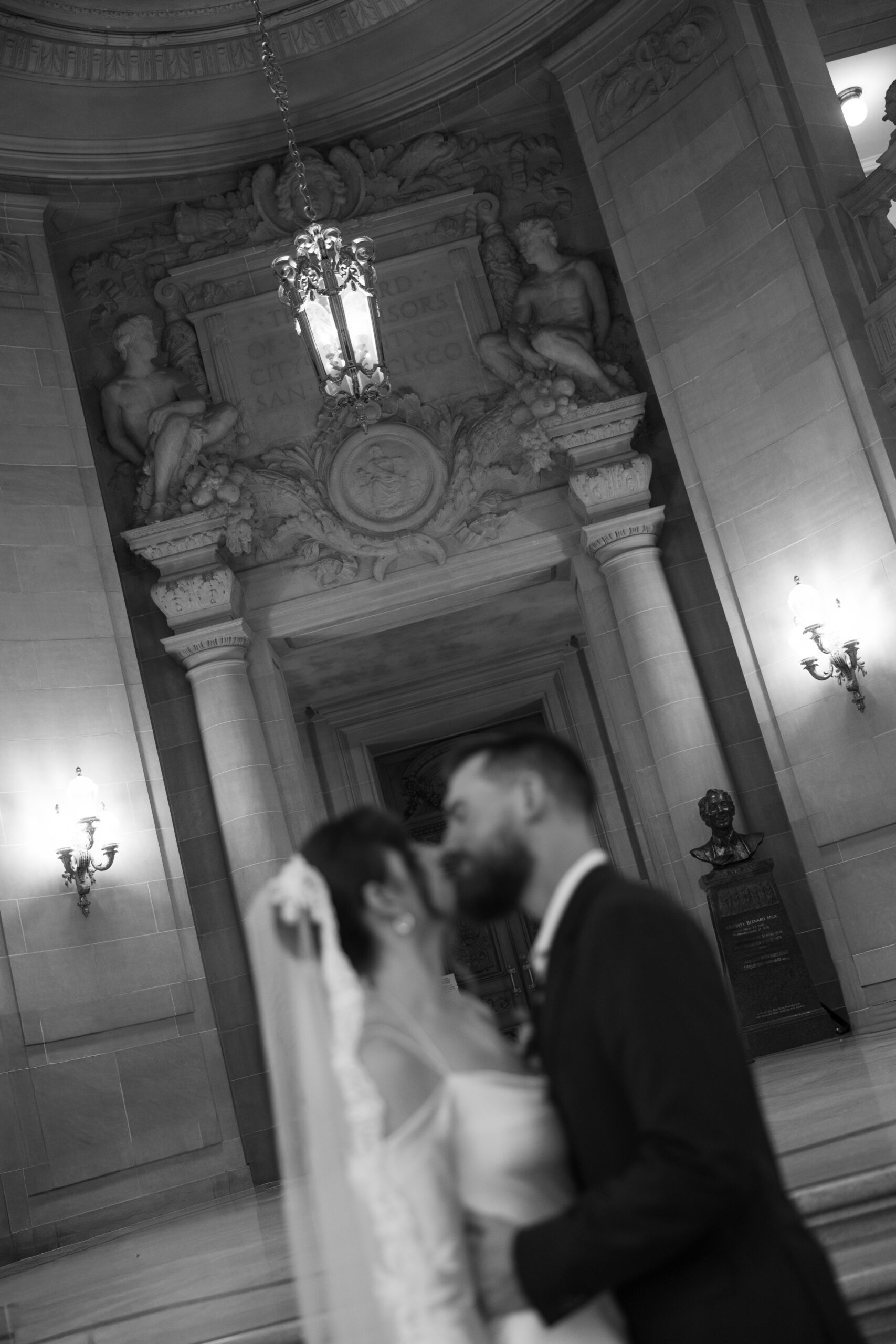 A blurry, unfocused photo of a bride and groom kissing, showing architecture at San Francisco City hall