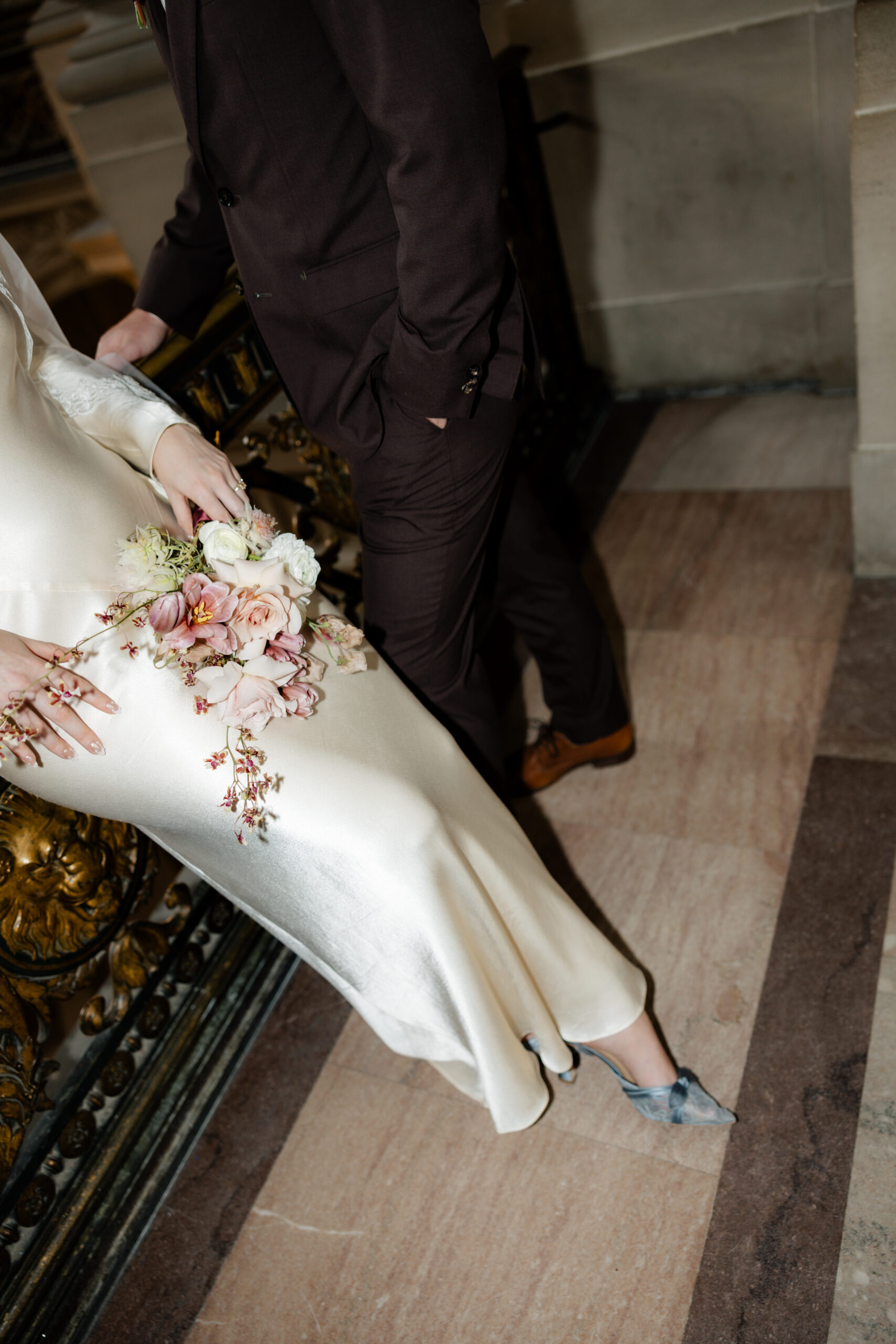 A bride holding her pink wedding bouquet and wearing blue wedding shoes