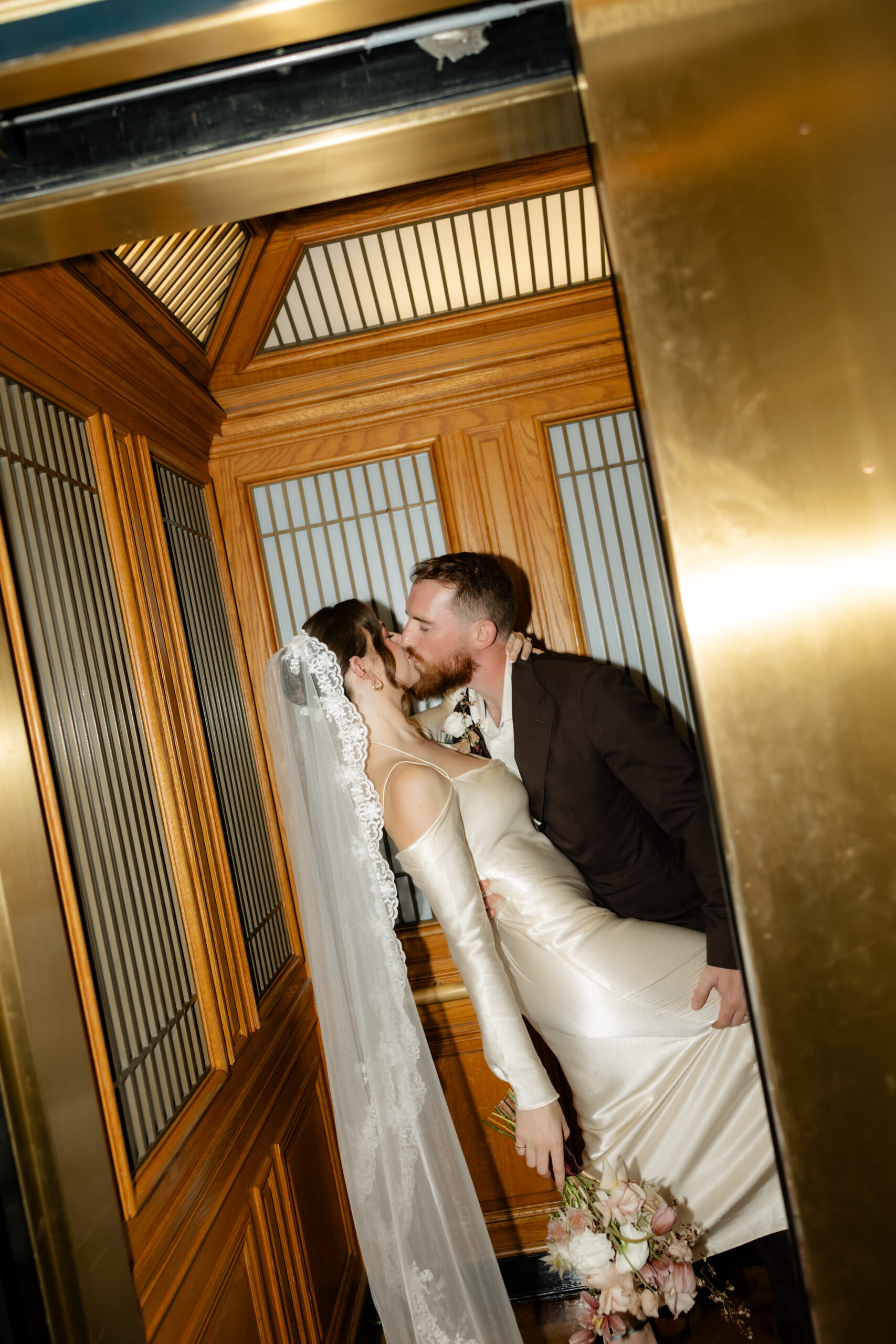 A photo of a bride and groom kissing in an elevator in San Francisco City Hall