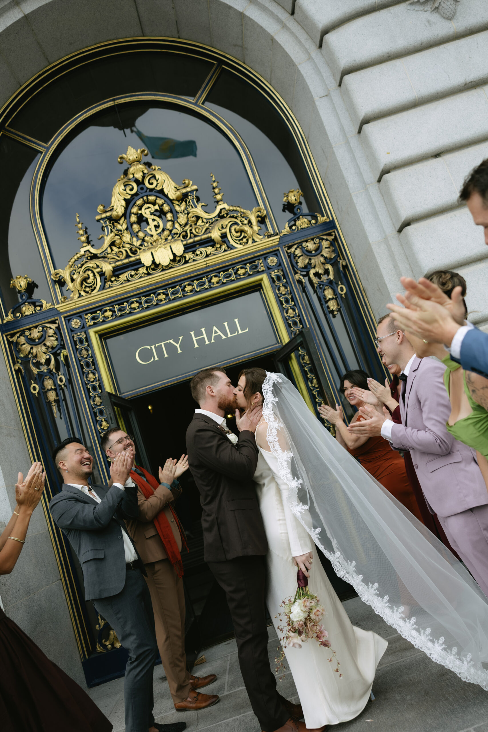 A wedding couple kissing in their grand exit from their San Francisco city hall wedding