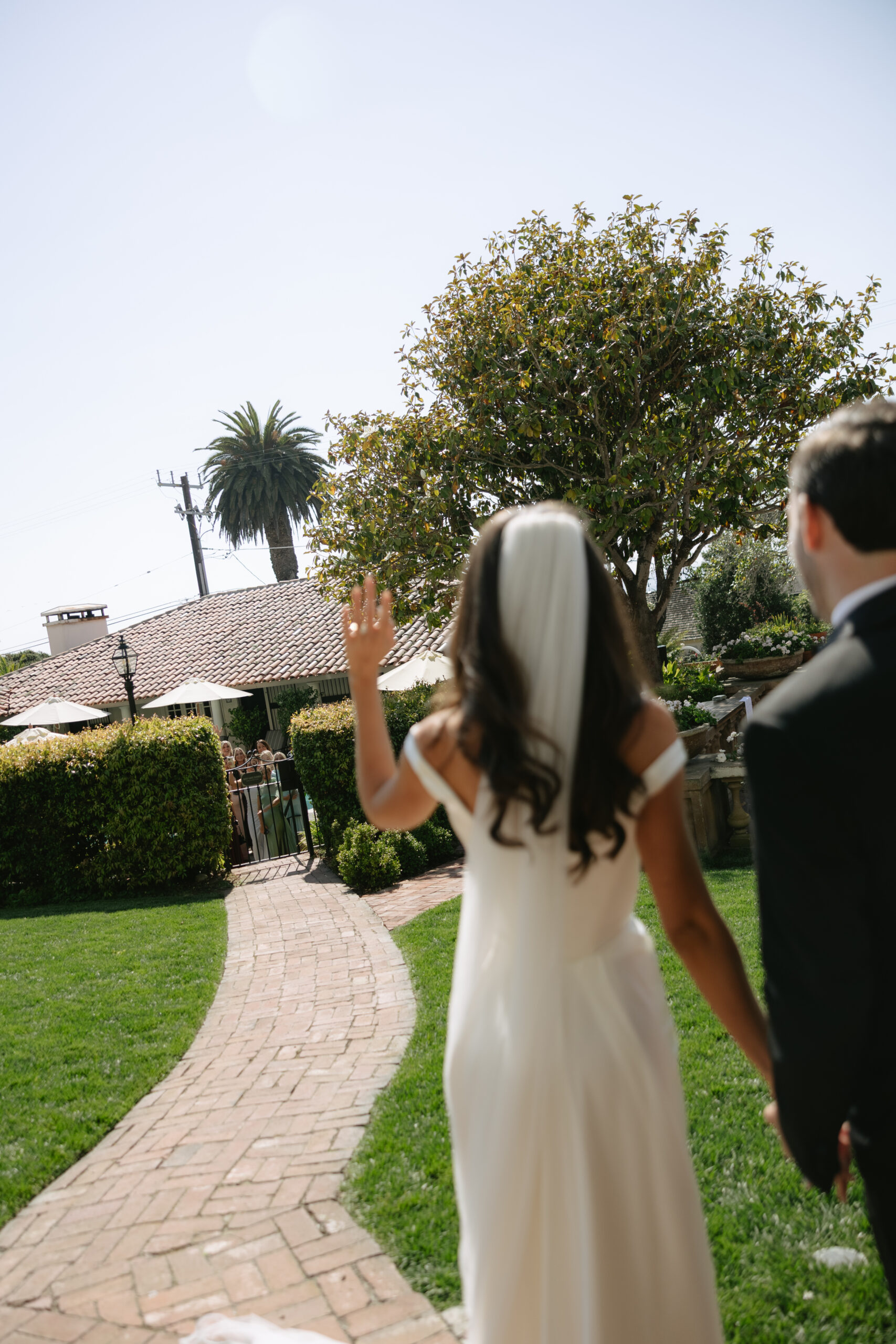 Bride and groom waving at wedding guests in candid wedding photos