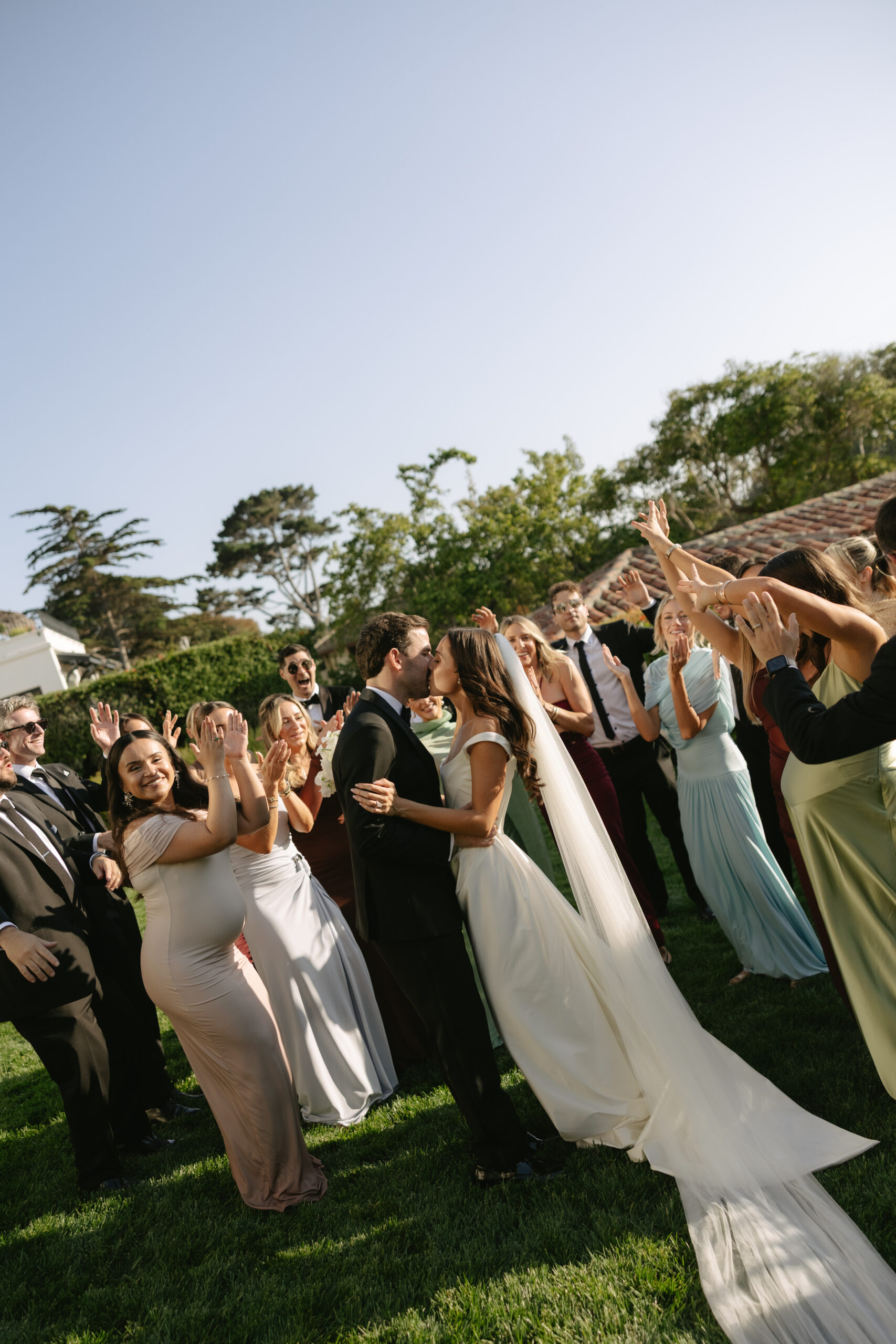 Bride and groom kissing while bridal party cheers