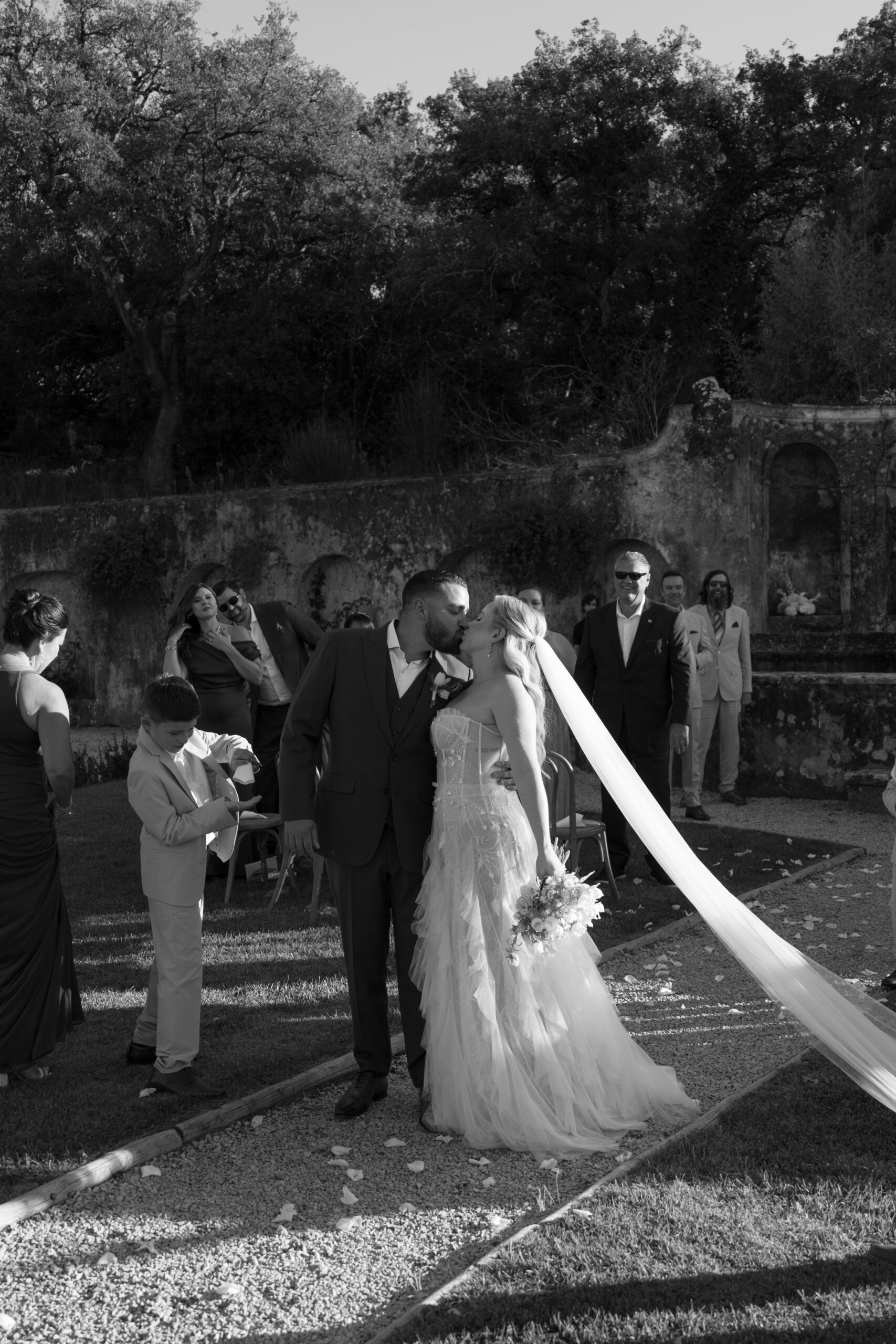 Black and white photo of bride and groom kissing after their wedding ceremony