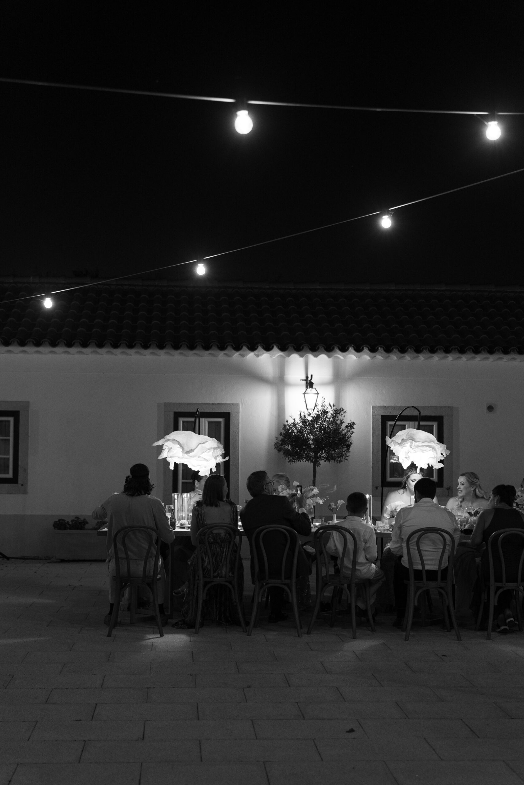 Black and white candid wedding photo of guests enjoying dinner