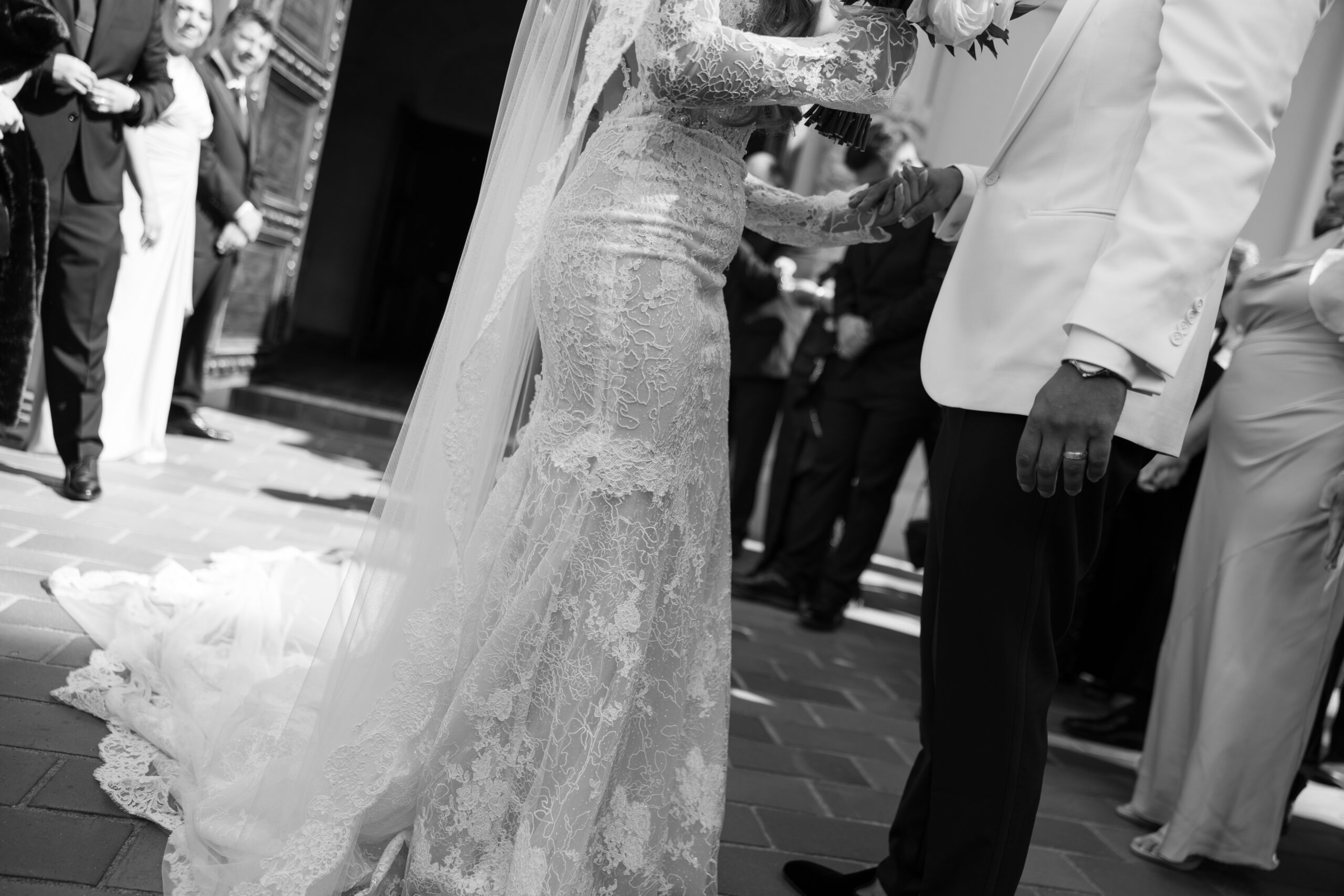 A black and white photo of a bride and groom holding hands