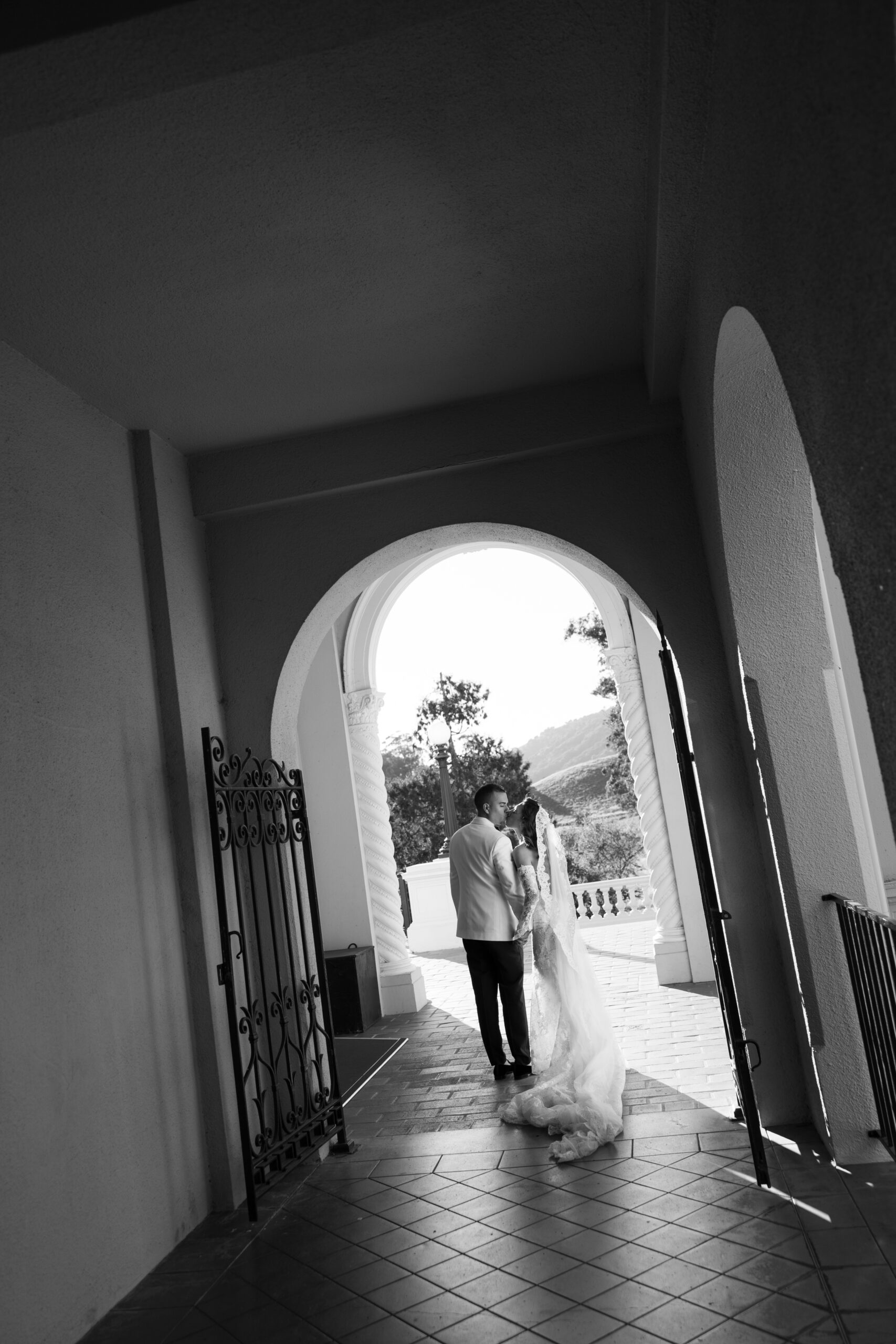 A bride and groom posing for wedding photos underneath an arch