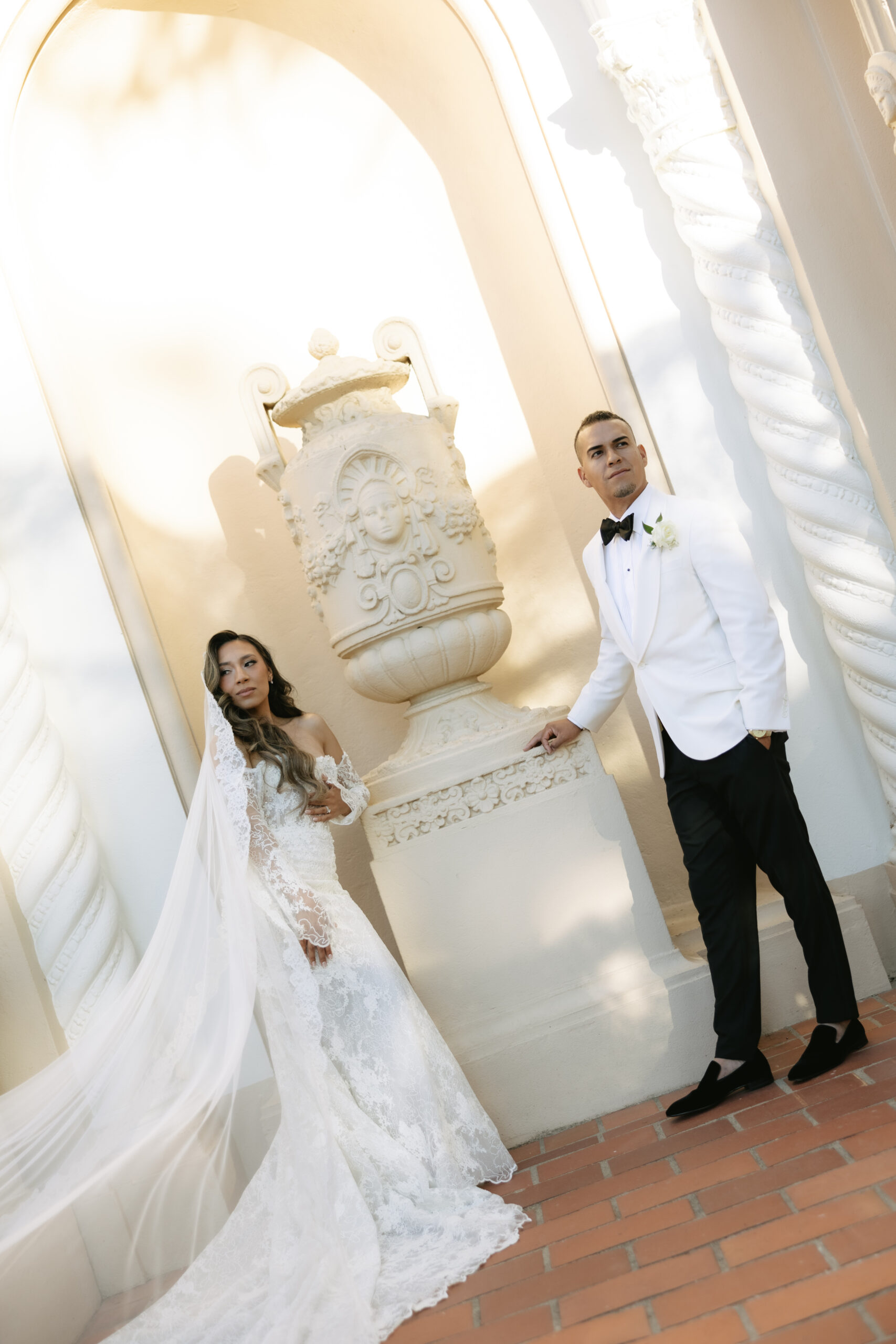 A bride and groom posing for wedding photos with architectural elements