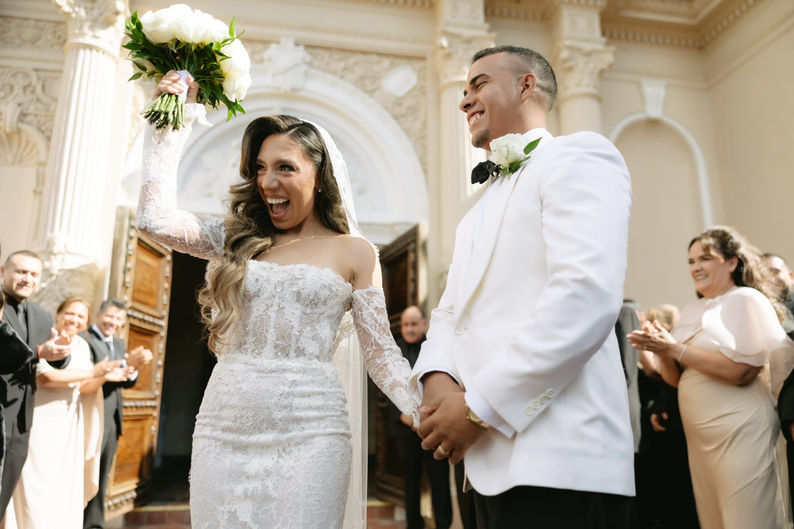 A couple cheering after exiting their Catholic wedding