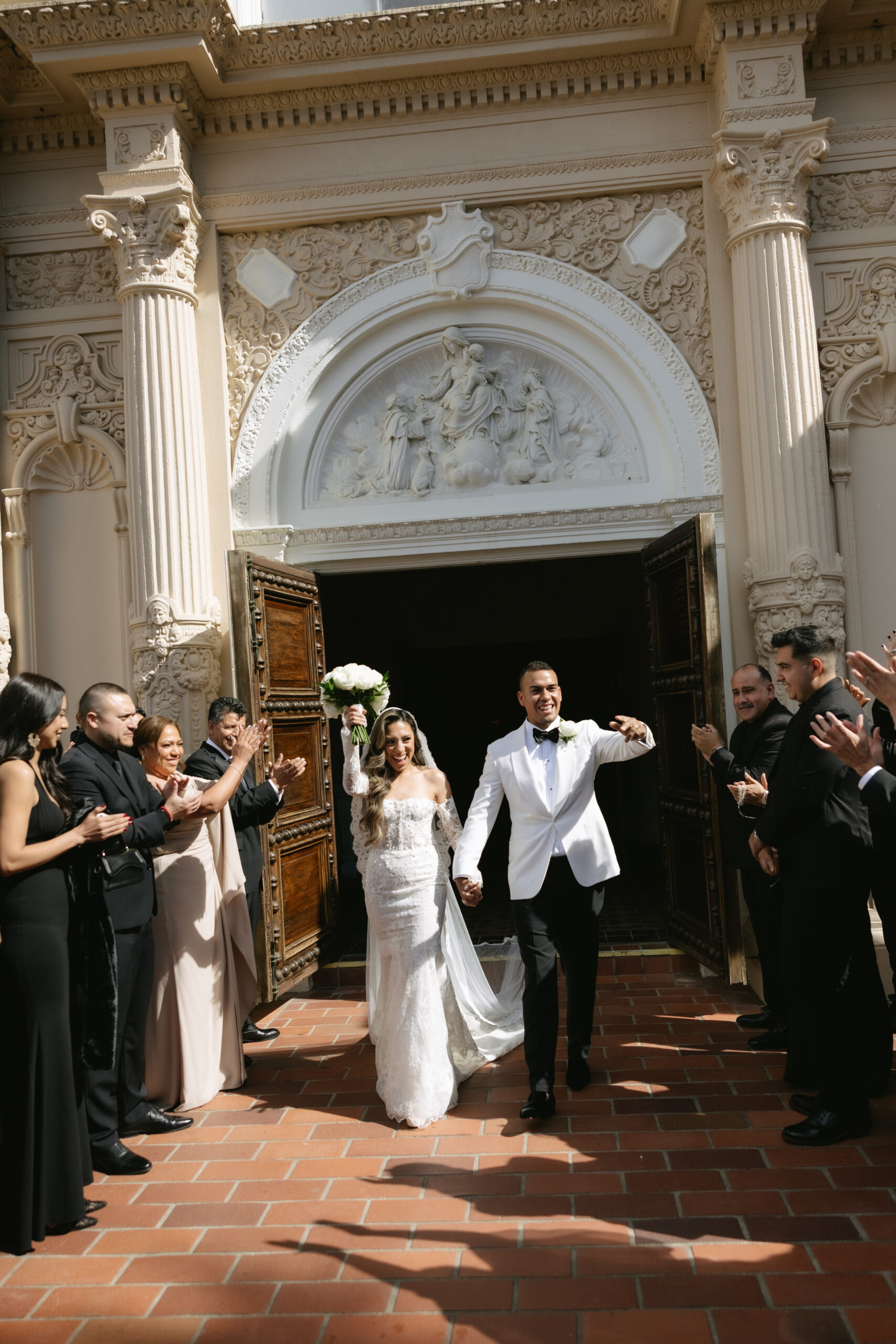 A bride and groom cheering as they exit their Catholic wedding