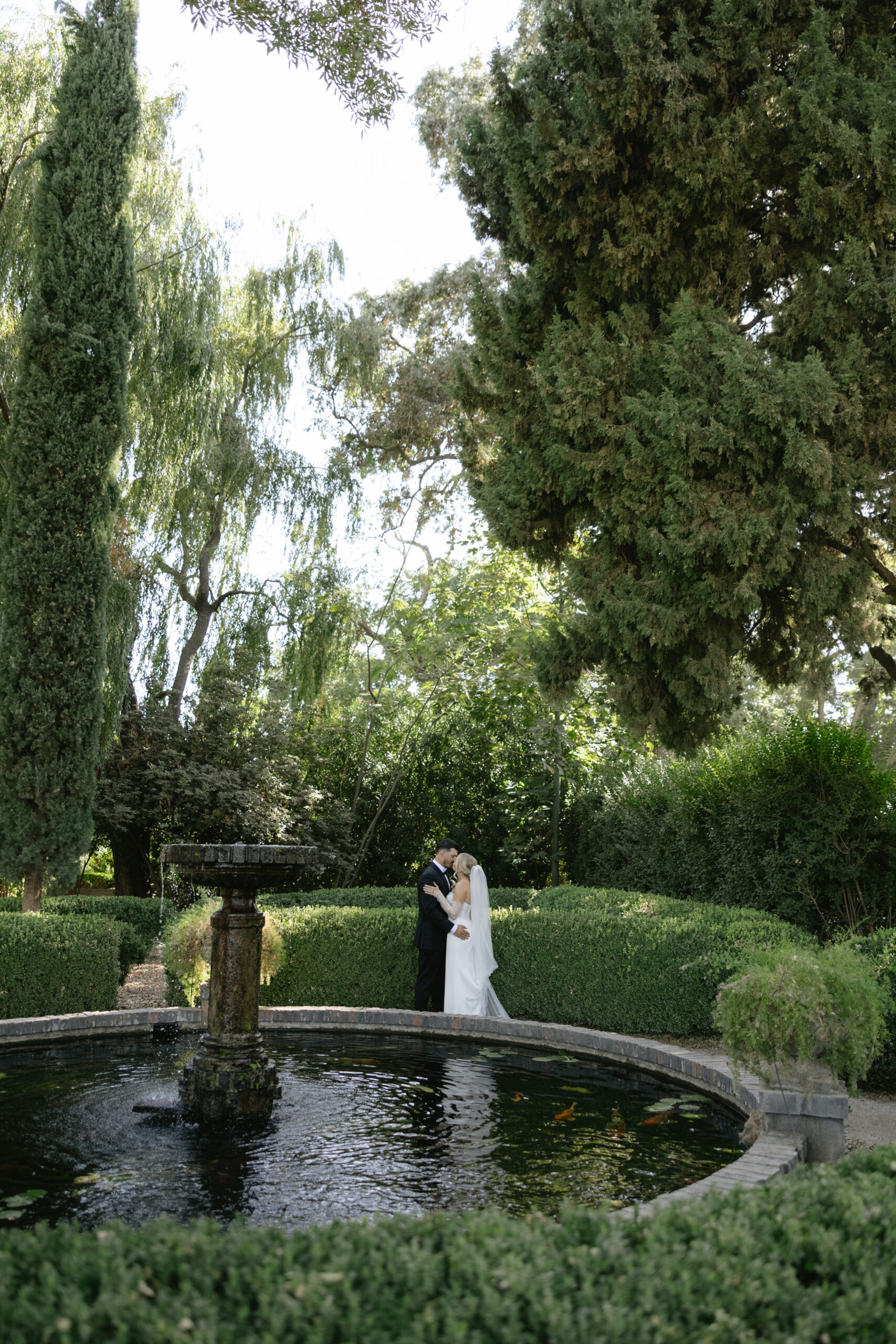 A couple kissing in wedding portraits near the fountain at Park Winters