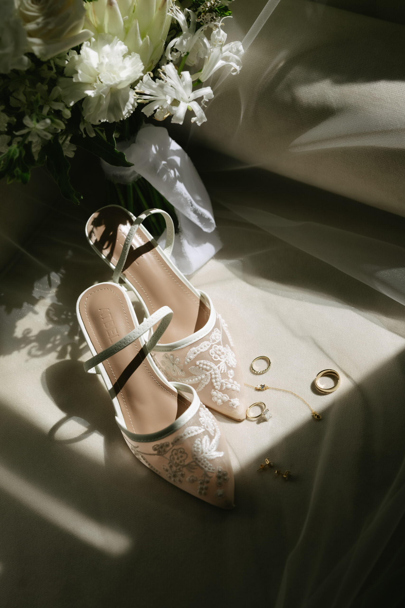 A wedding detail photo of bride's shoes, jewelry, and wedding bouquet