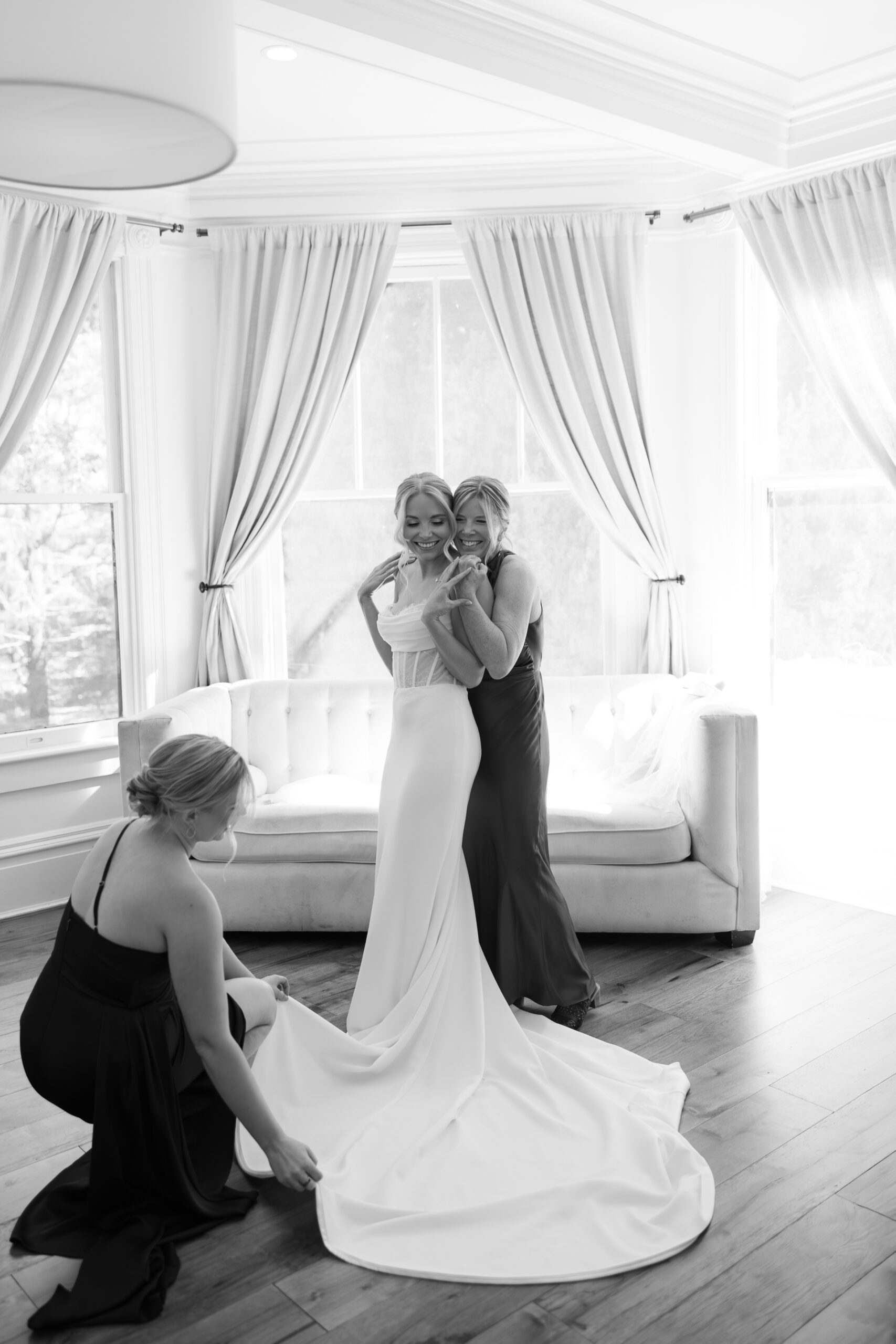 A mom and sister helping a bride get ready for her wedding