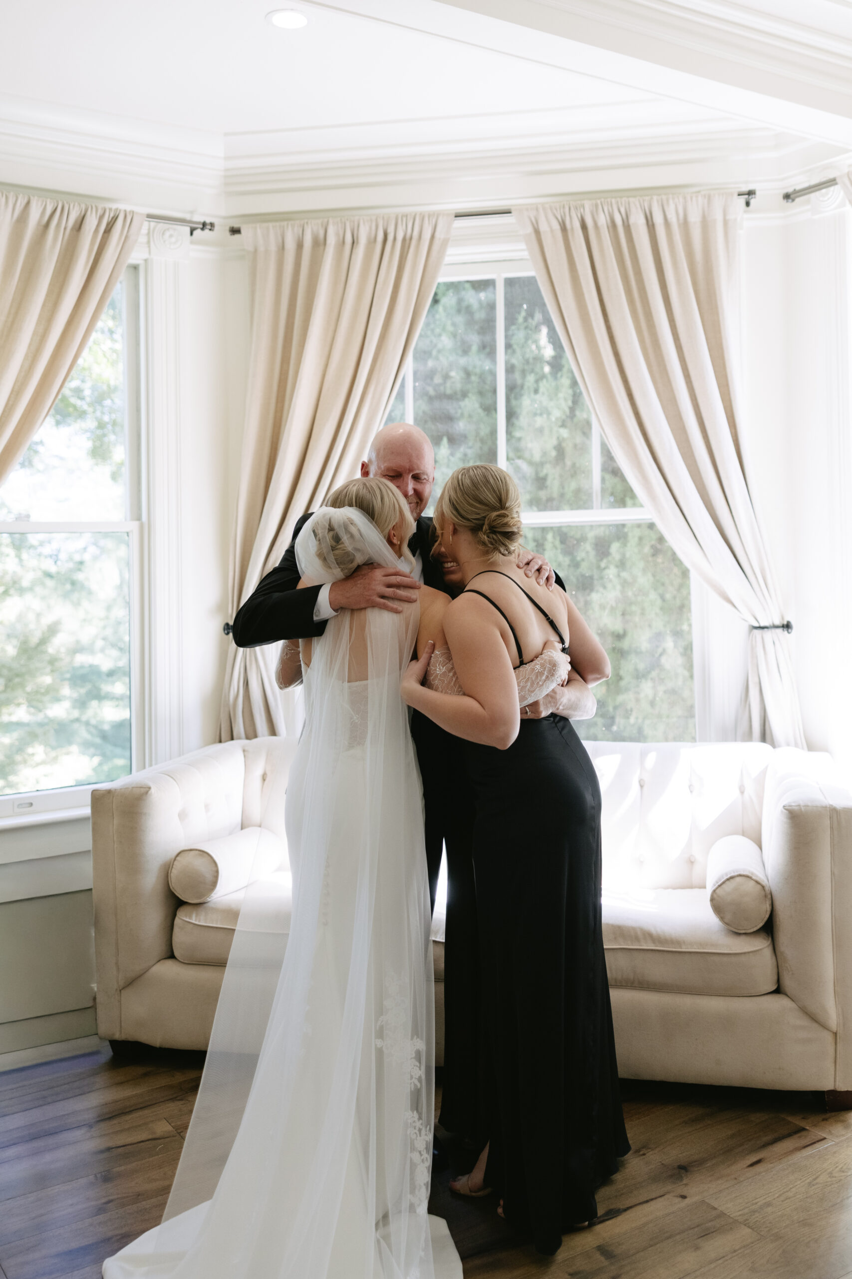 A bride hugging her parents and sister during getting ready wedding photos 