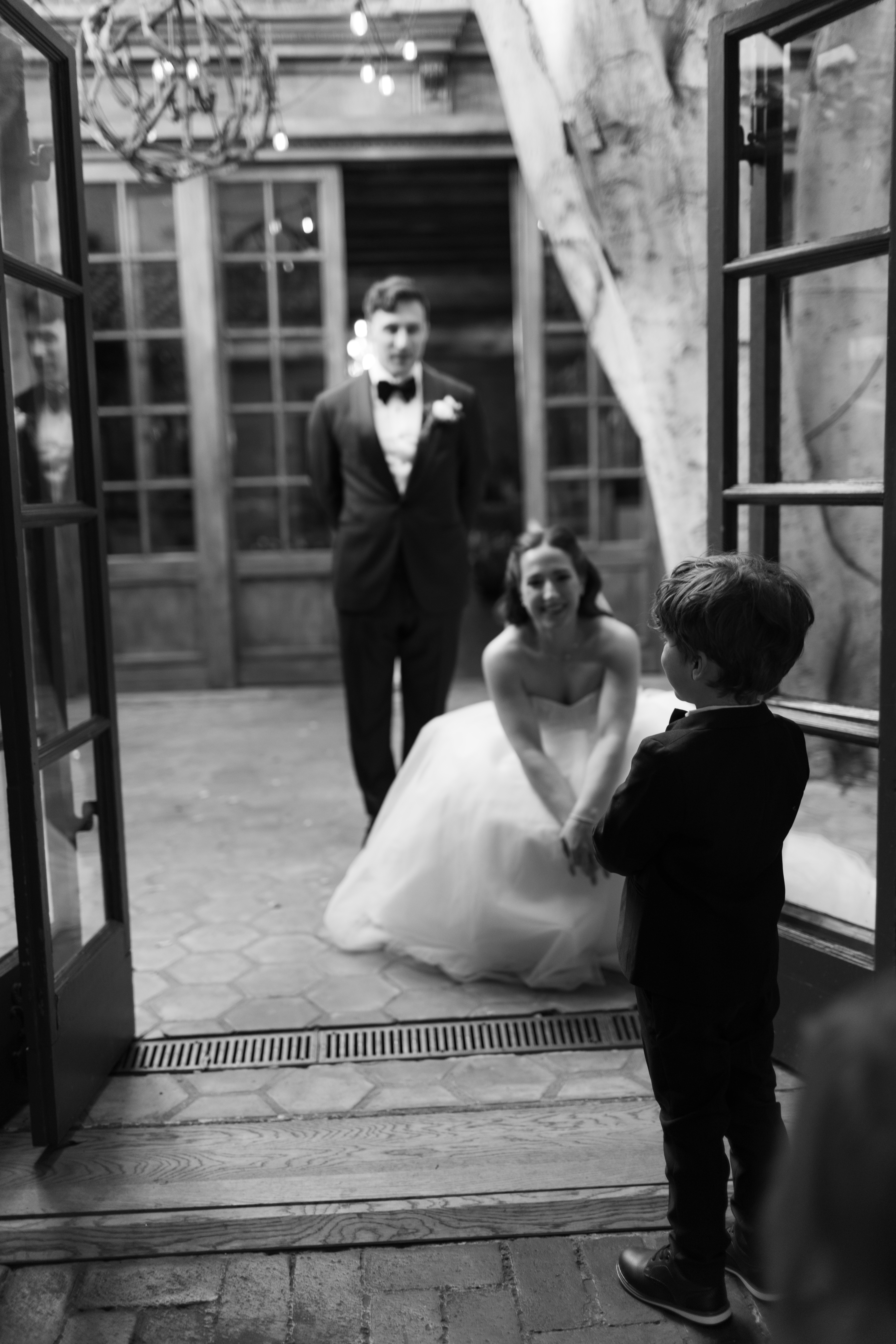 A bride and groom talking to a ring bearer captured through documentary style wedding photography
