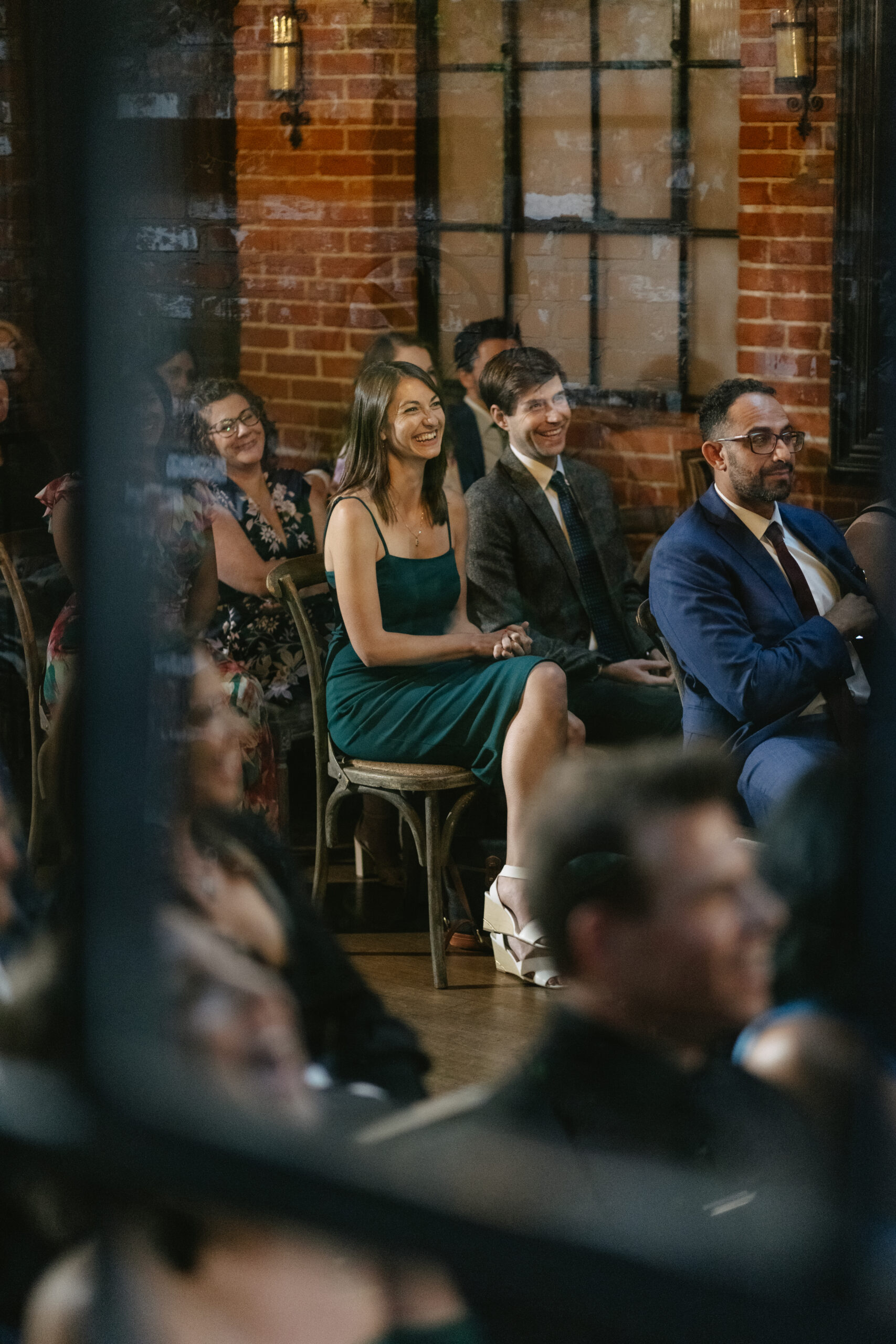 A candid wedding photo of guests watching a wedding ceremony