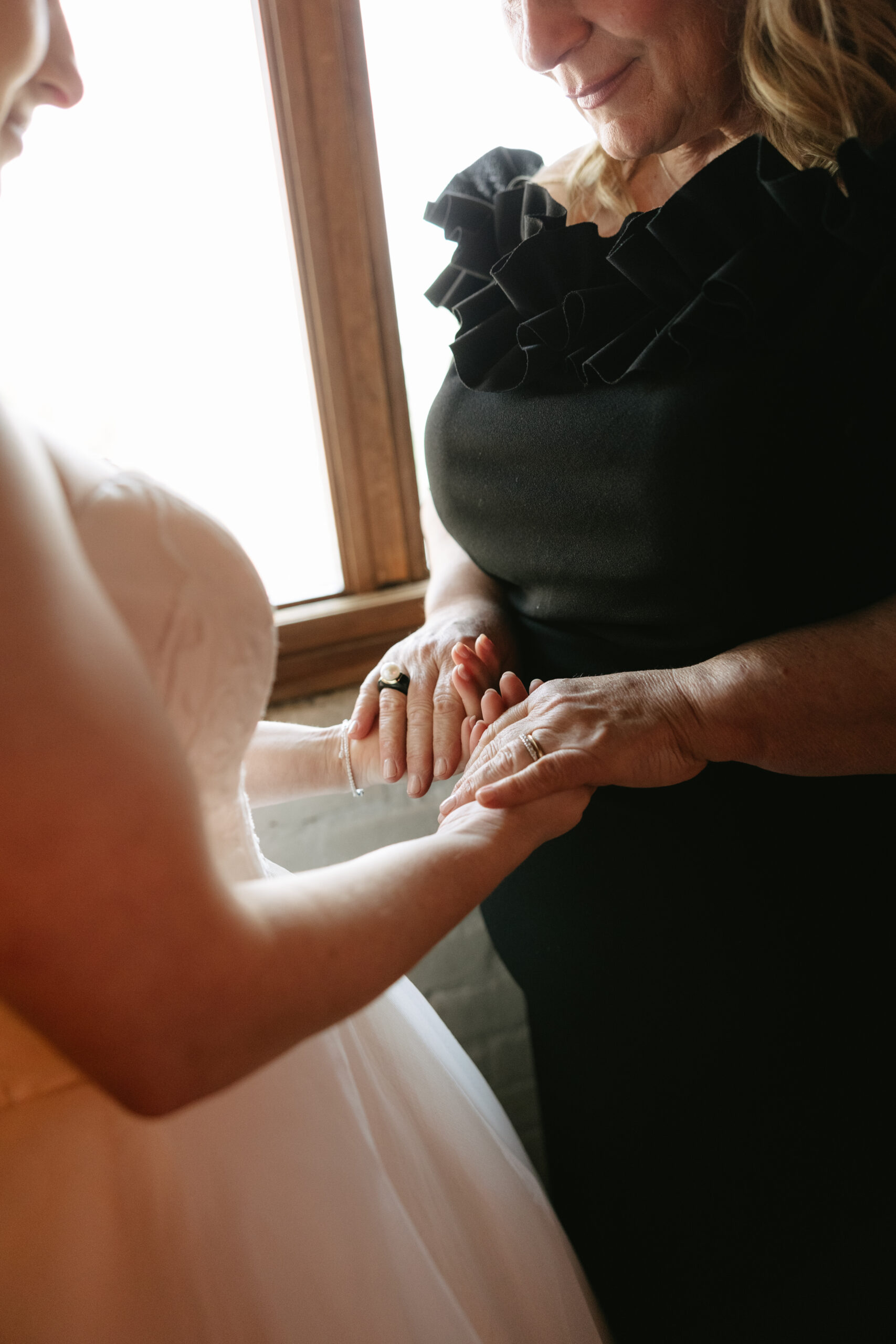 A mother of the bride holding hands with her daughter