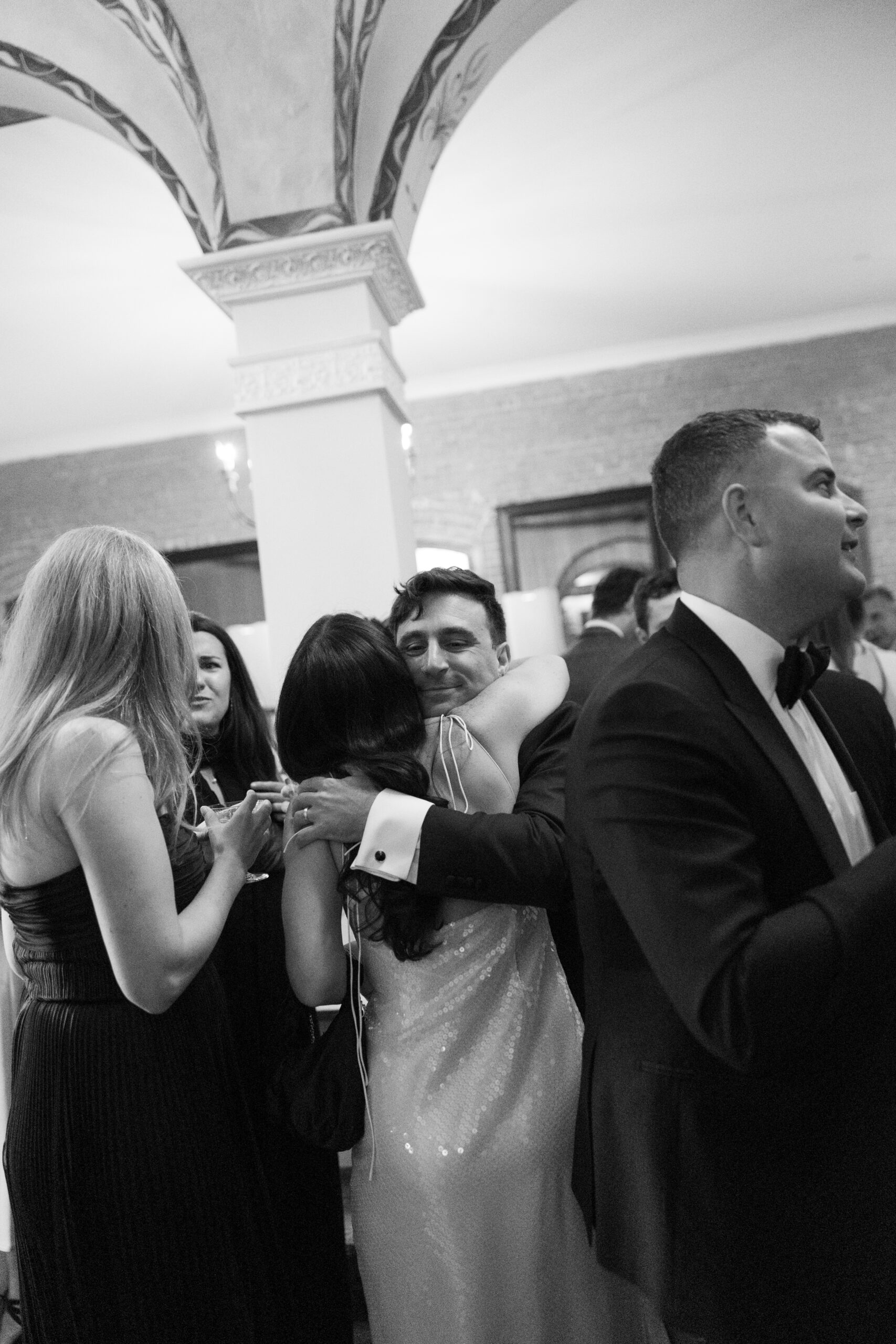 A groom hugging a wedding guest captured through documentary style wedding photography