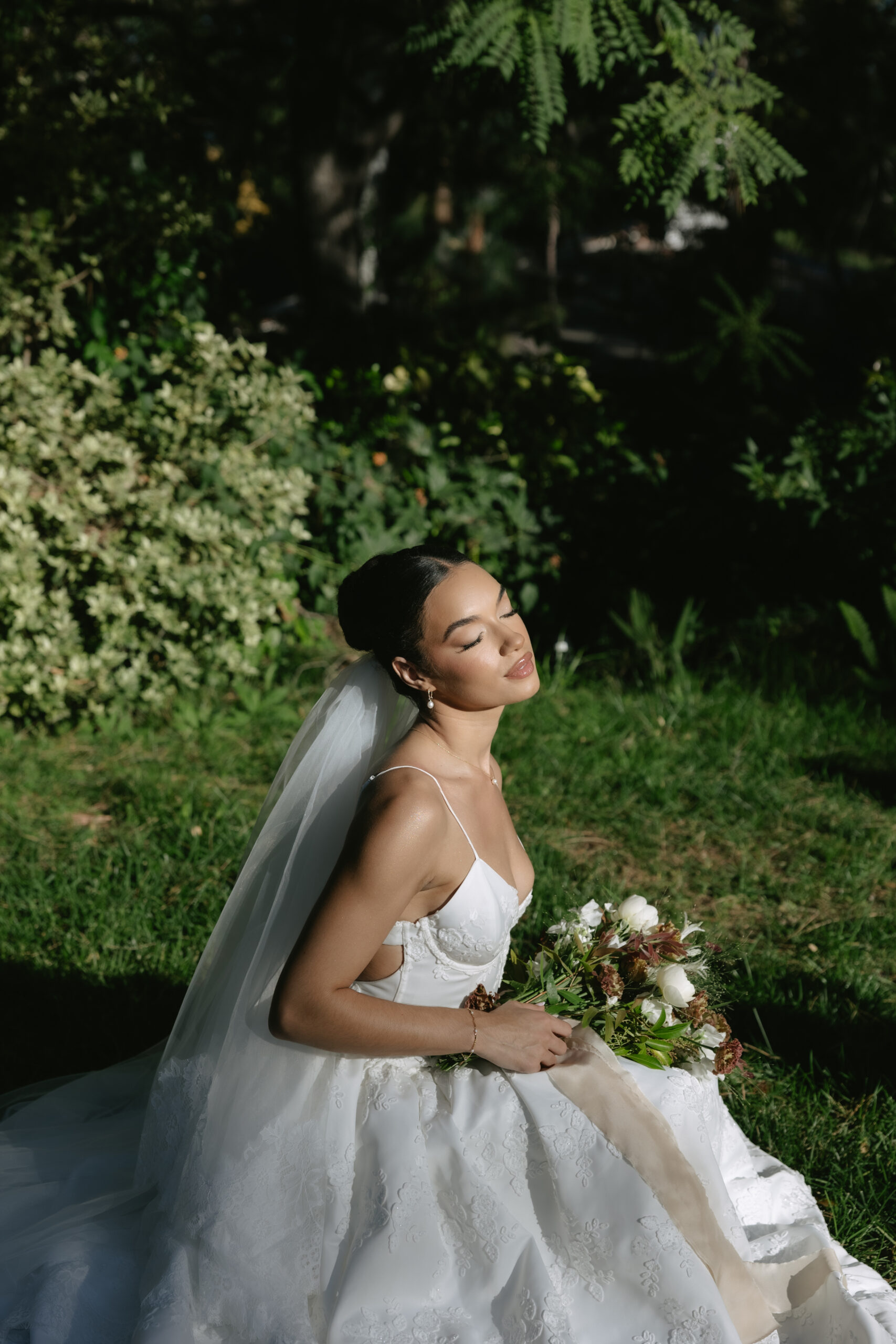A bride sitting on the grass in a wedding dress for a styled shoot