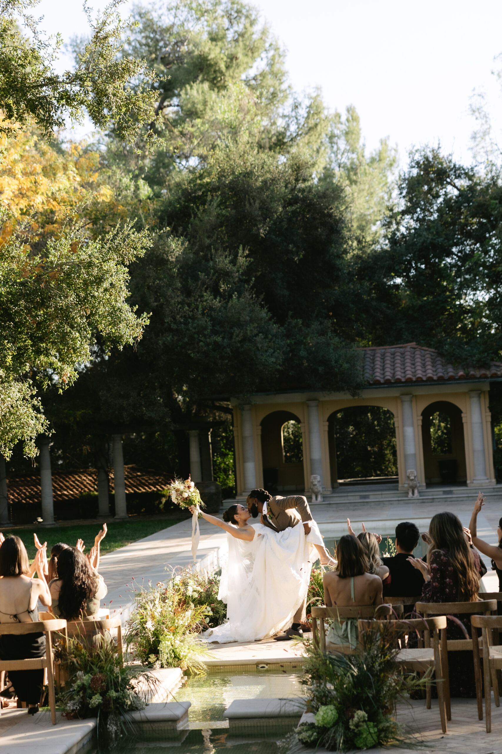 Guests cheering while a bride and groom share their first kiss