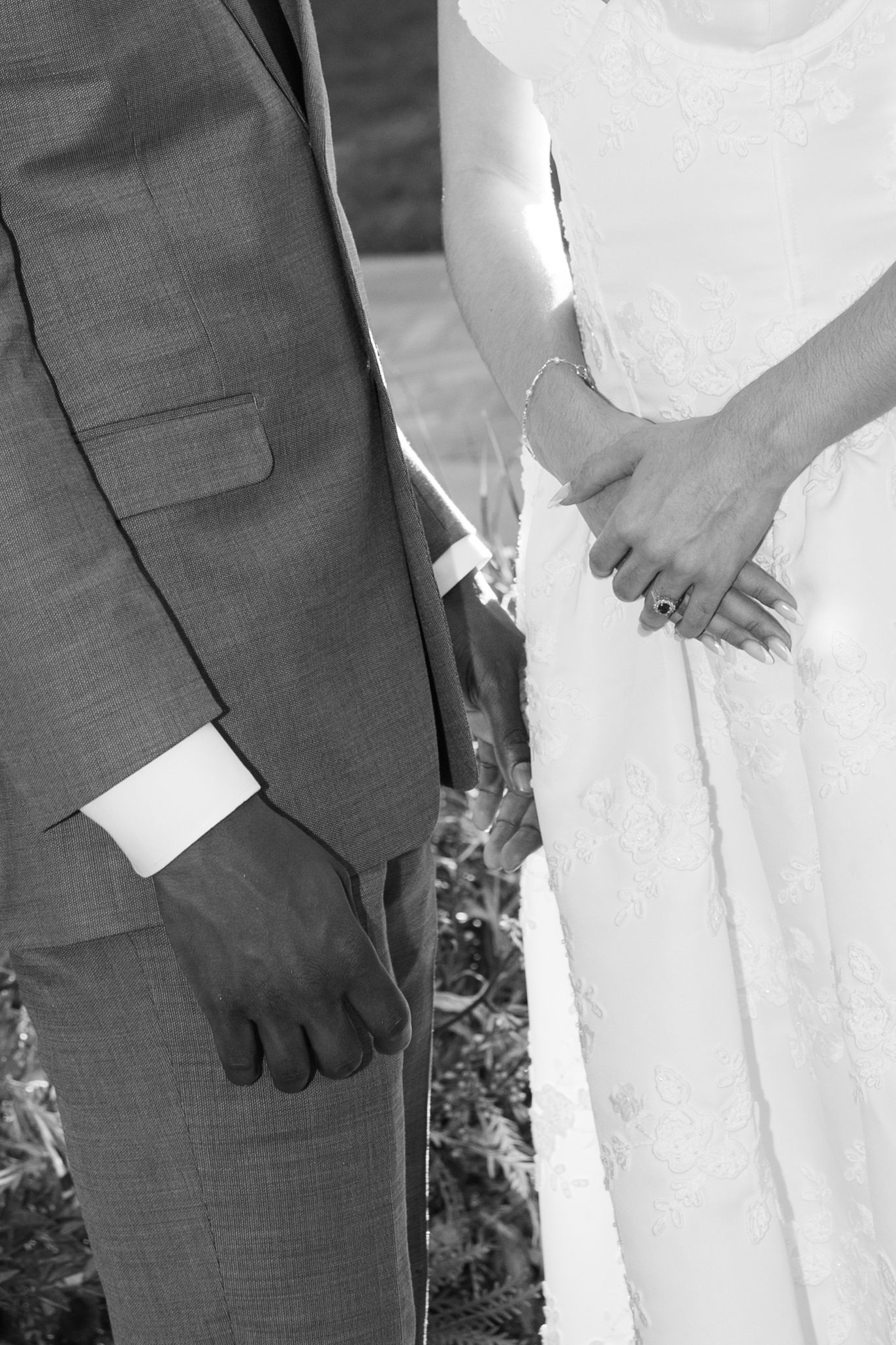 A black and white up close photo of a wedding dress and groom suit