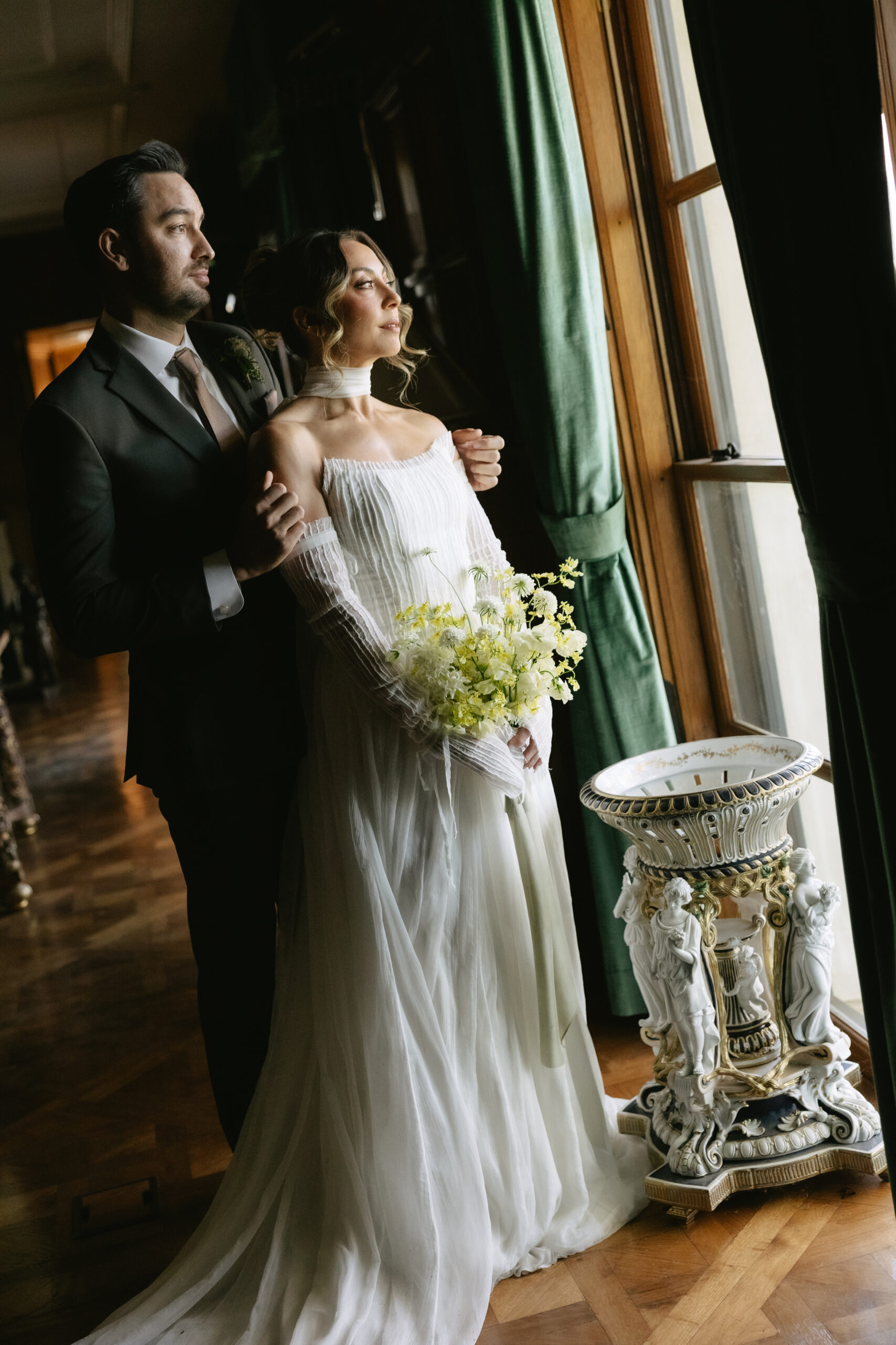 A bride and groom looking out a window from inside etienne estate