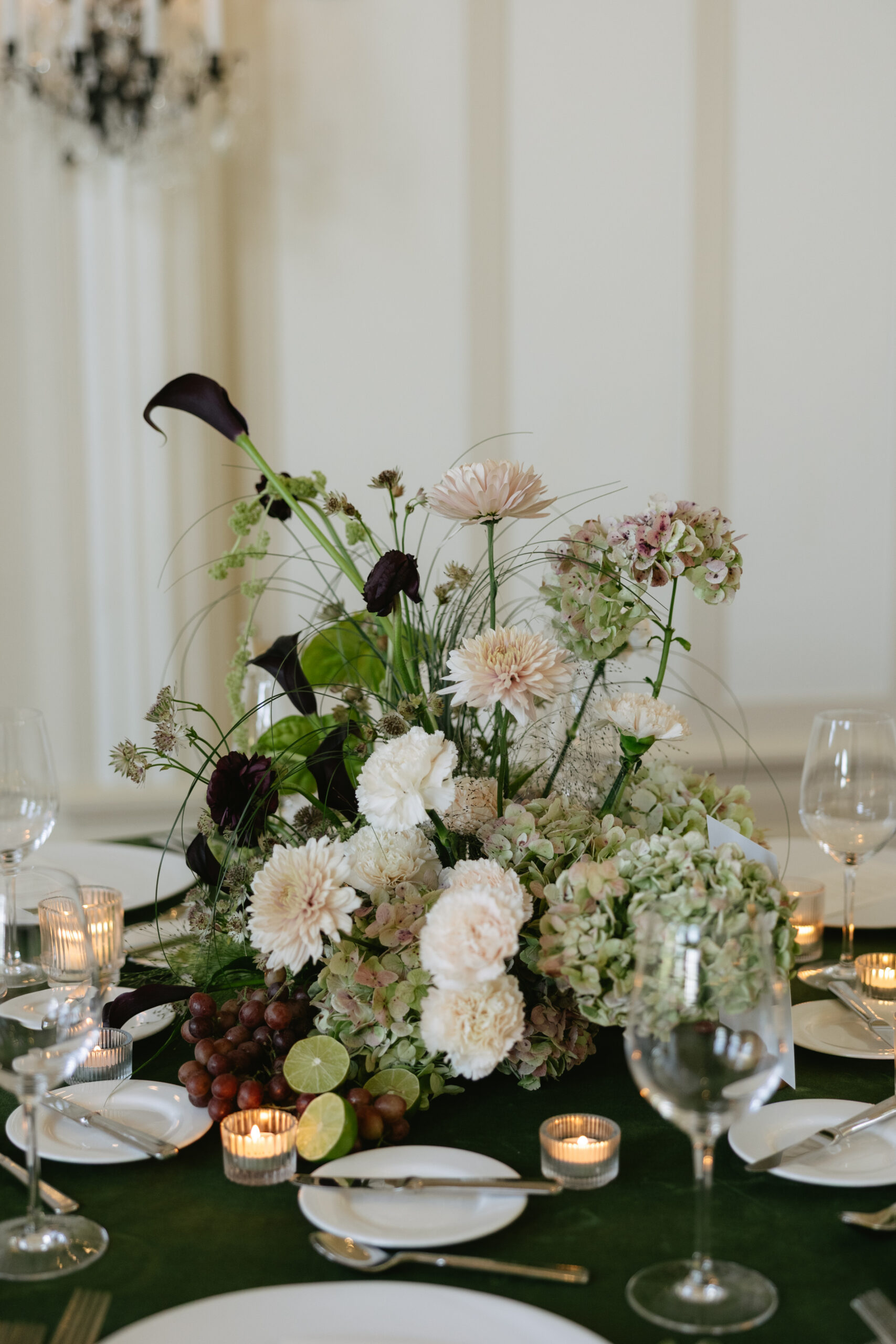 A wedding table centerpiece with calla lilies and more flowers and fresh fruit
